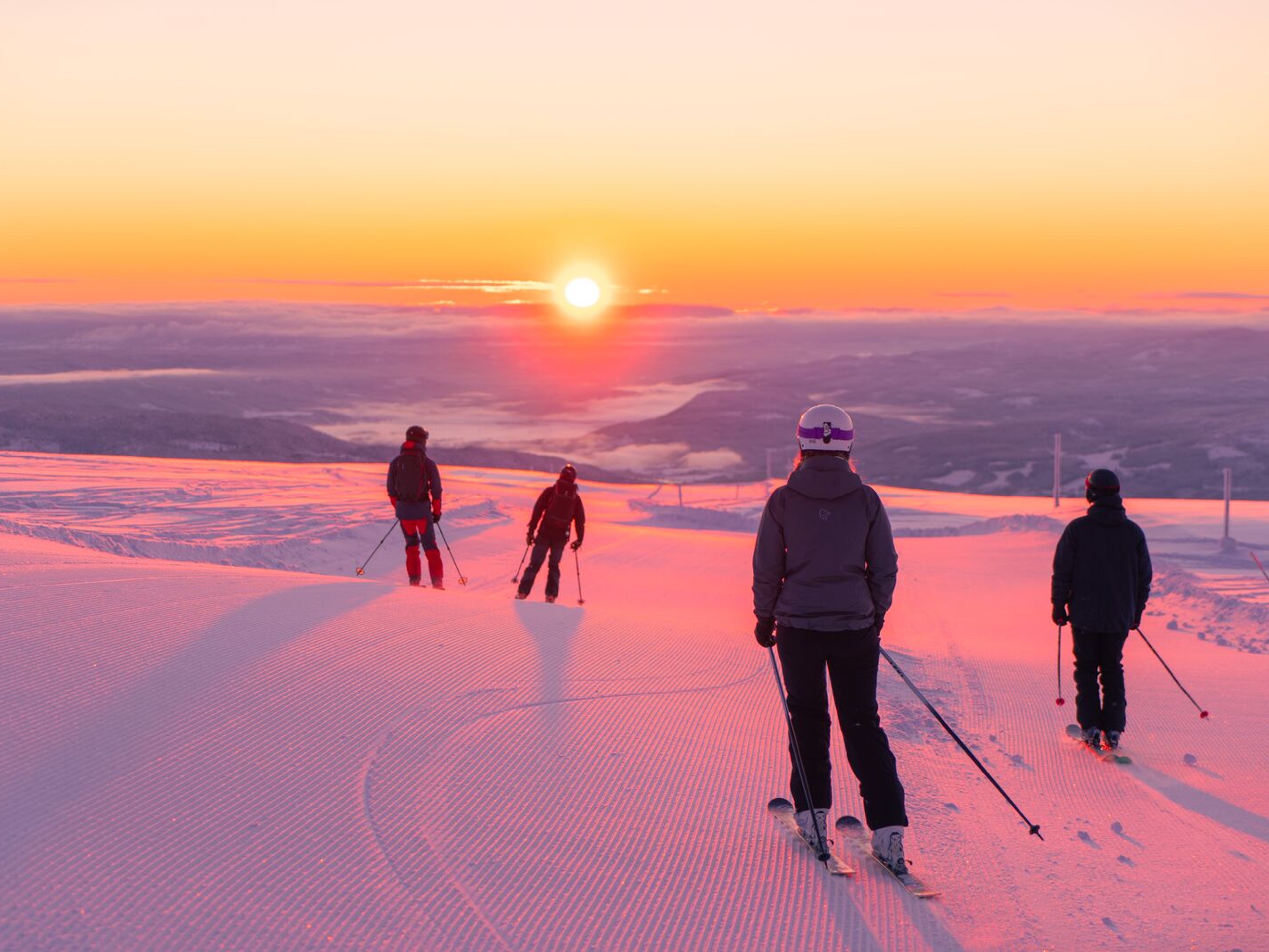 Four people skiing downhill in sunrise at Norefjell ski resort, Eastern Norway