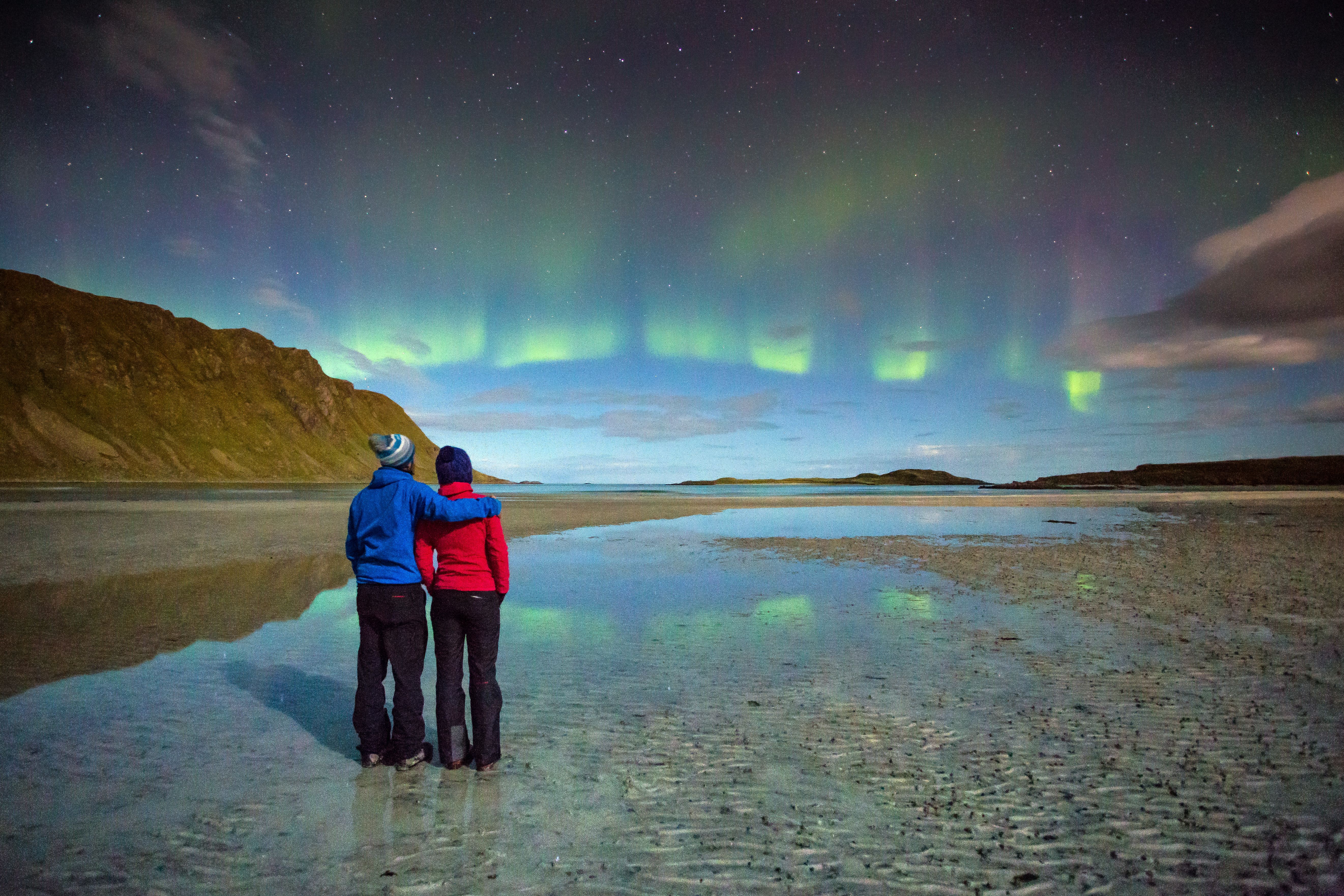 Green northern lights over an empty beach at Fredvang on the Lofoten islands in Northern Norway