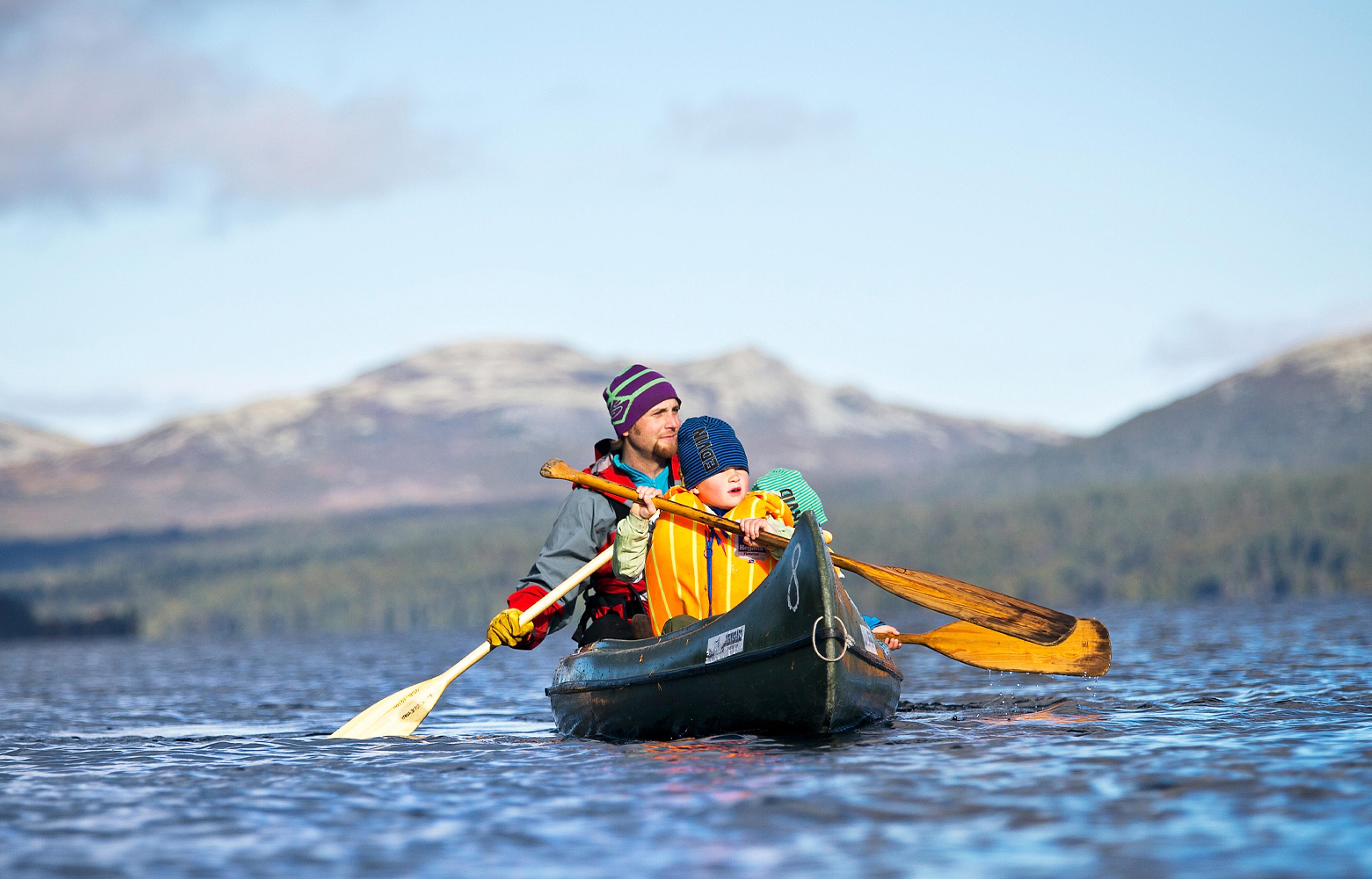 Padre e hijo montan en canoa durante una aventura en plena naturaleza para toda la familia en Femund Engerdal, Noruega.