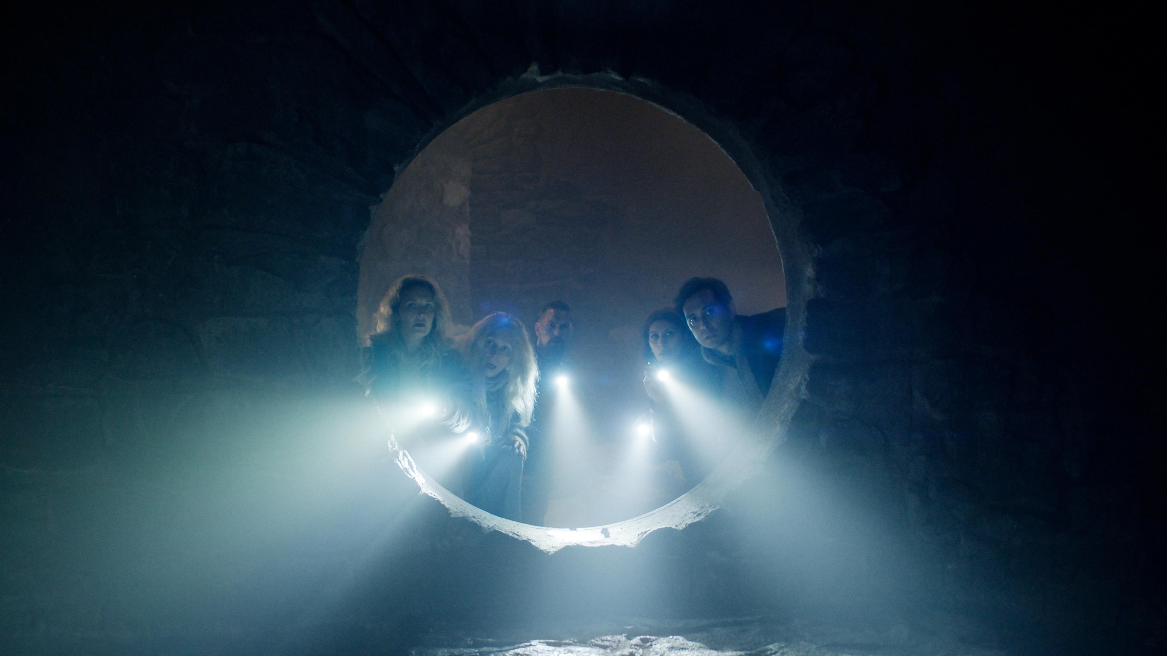 The cast of Troll 2 standing close together, holding flashlights and looking shocked