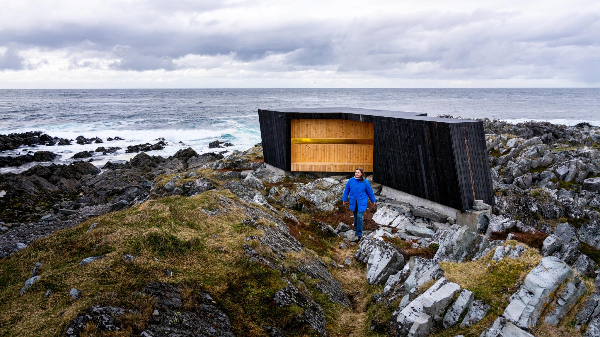 A woman outside of a birdwatching hide made by Biotope in Hamningberg, Varanger, Northern Norway