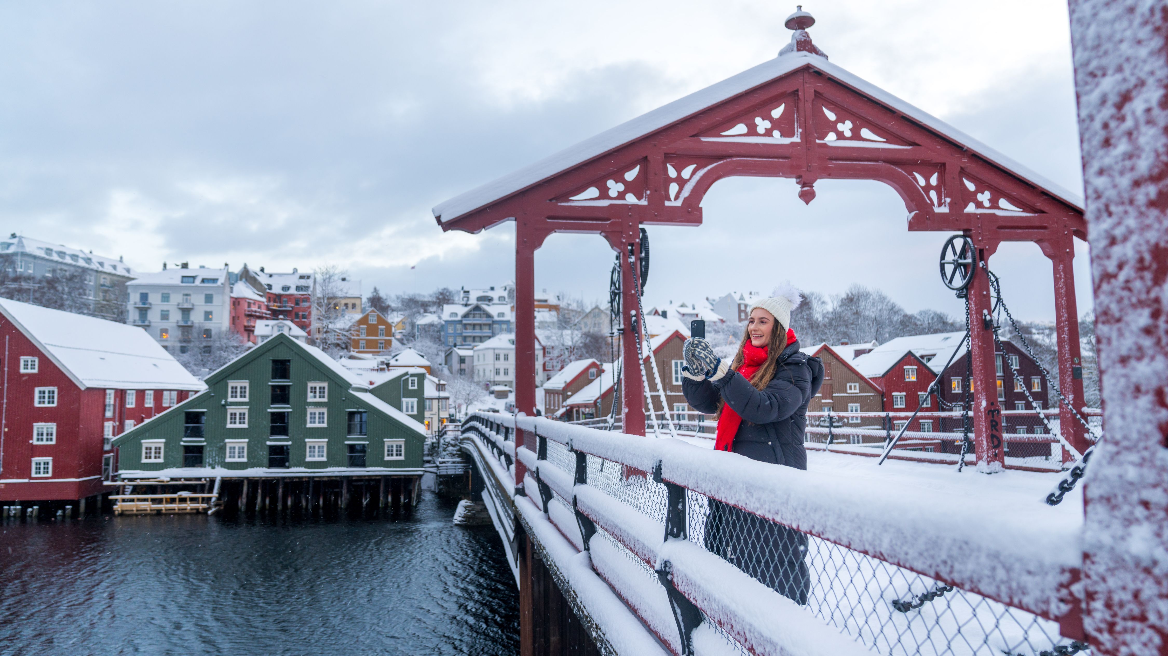A women taking a picture from the Old Town Bridge in Trondheim in winter, Trøndelag, Norway.