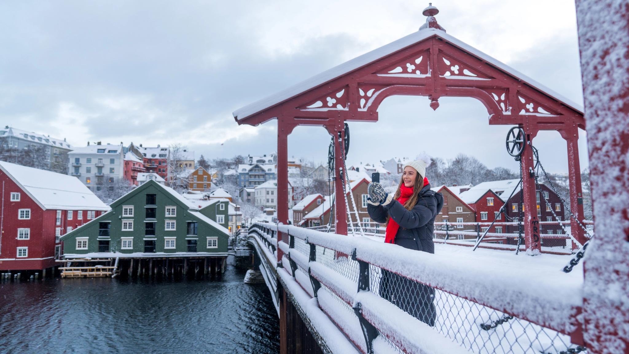 A women taking a picture from the Old Town Bridge in Trondheim in winter, Trøndelag, Norway.