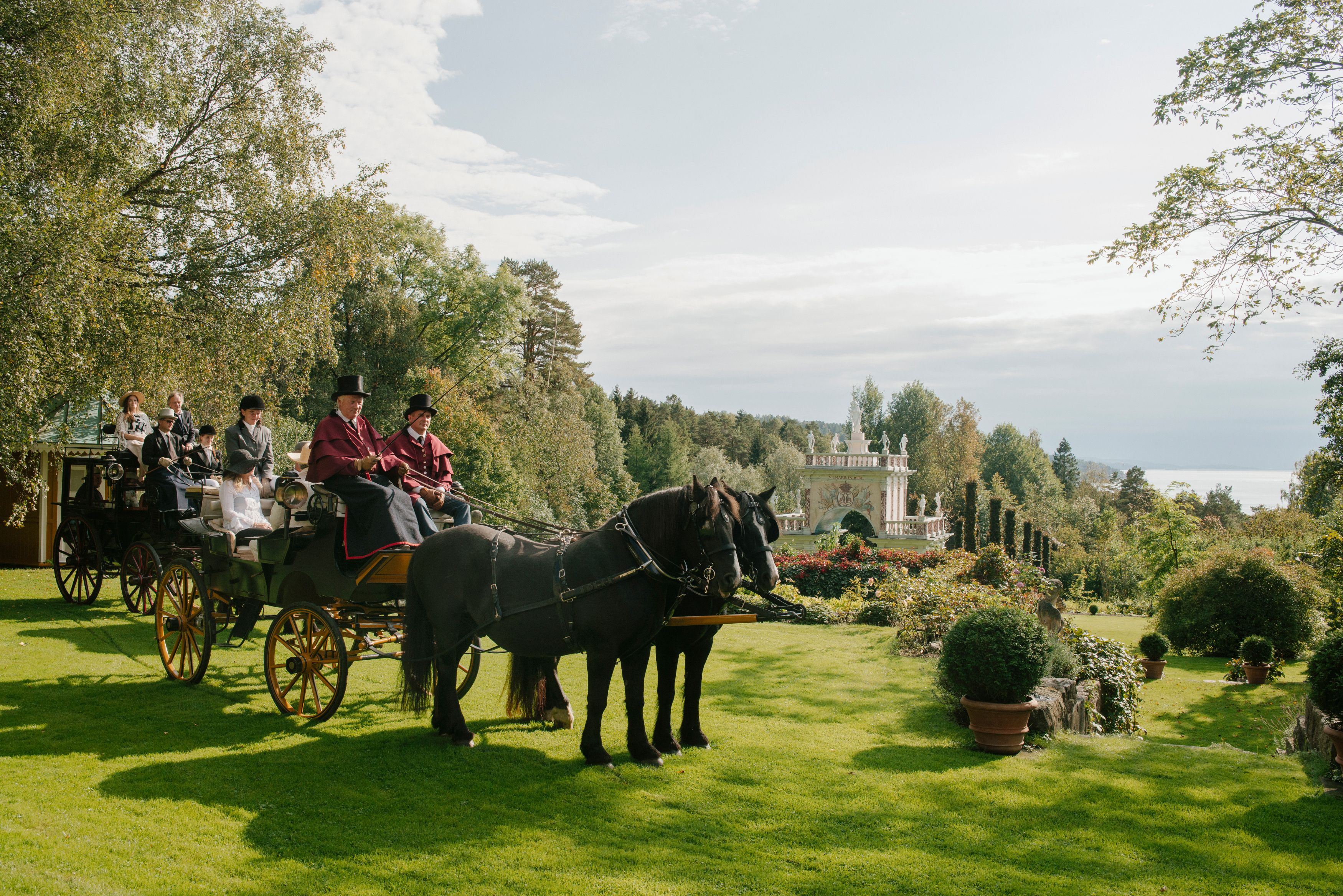 People in a horse-drawn carriage in the Havlystparken park at the culture destination Ramme Gård in Hvitsten by the Oslofjord in Eastern Norway