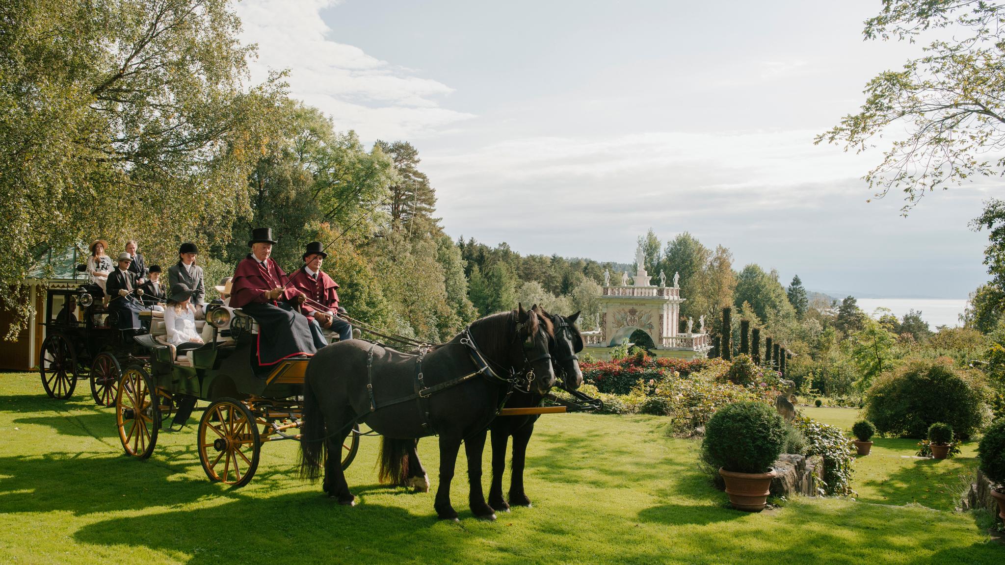 People in a horse-drawn carriage in the Havlystparken park at the culture destination Ramme Gård in Hvitsten by the Oslofjord in Eastern Norway