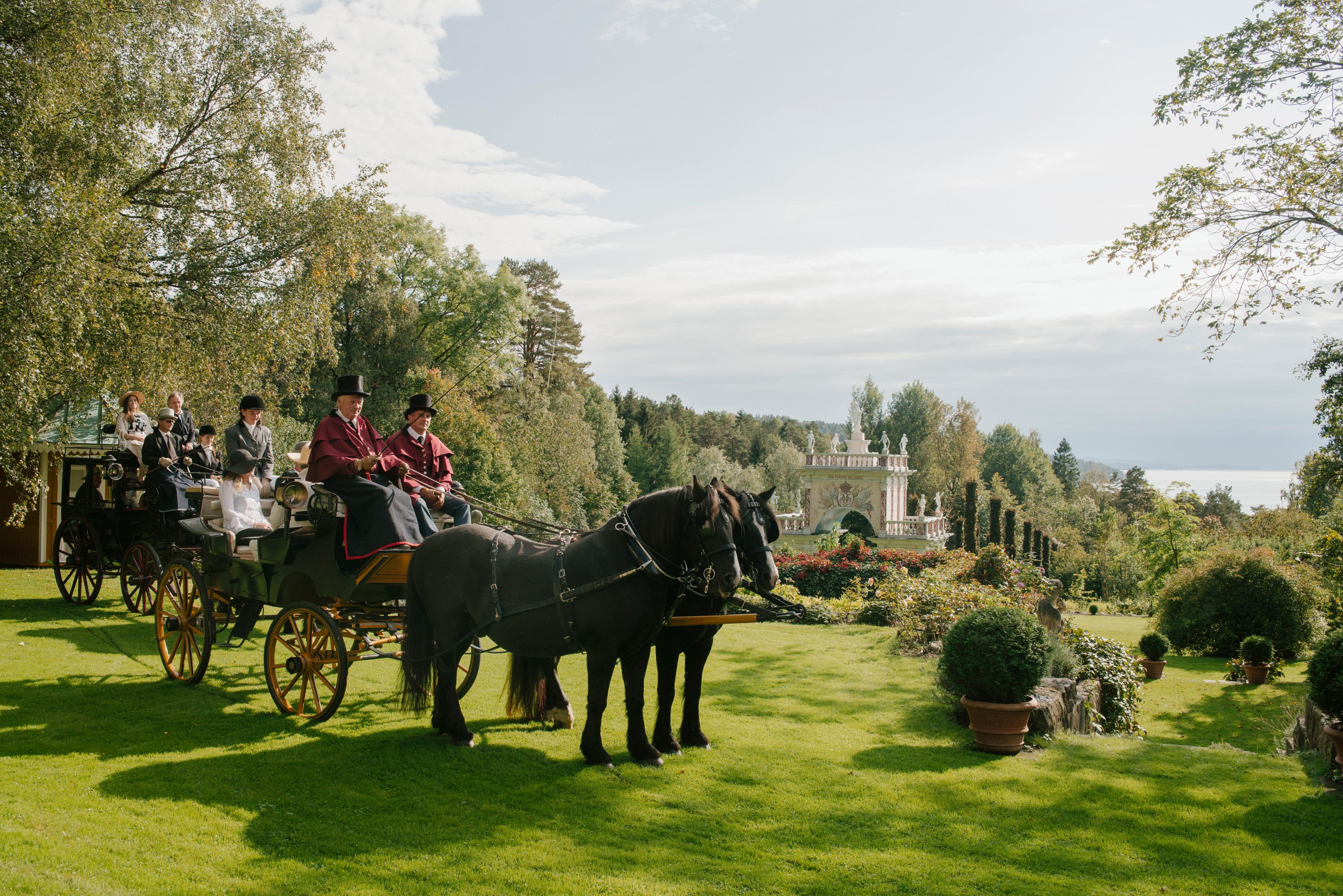 People in a horse-drawn carriage in the Havlystparken park at the culture destination Ramme Gård in Hvitsten by the Oslofjord in Eastern Norway