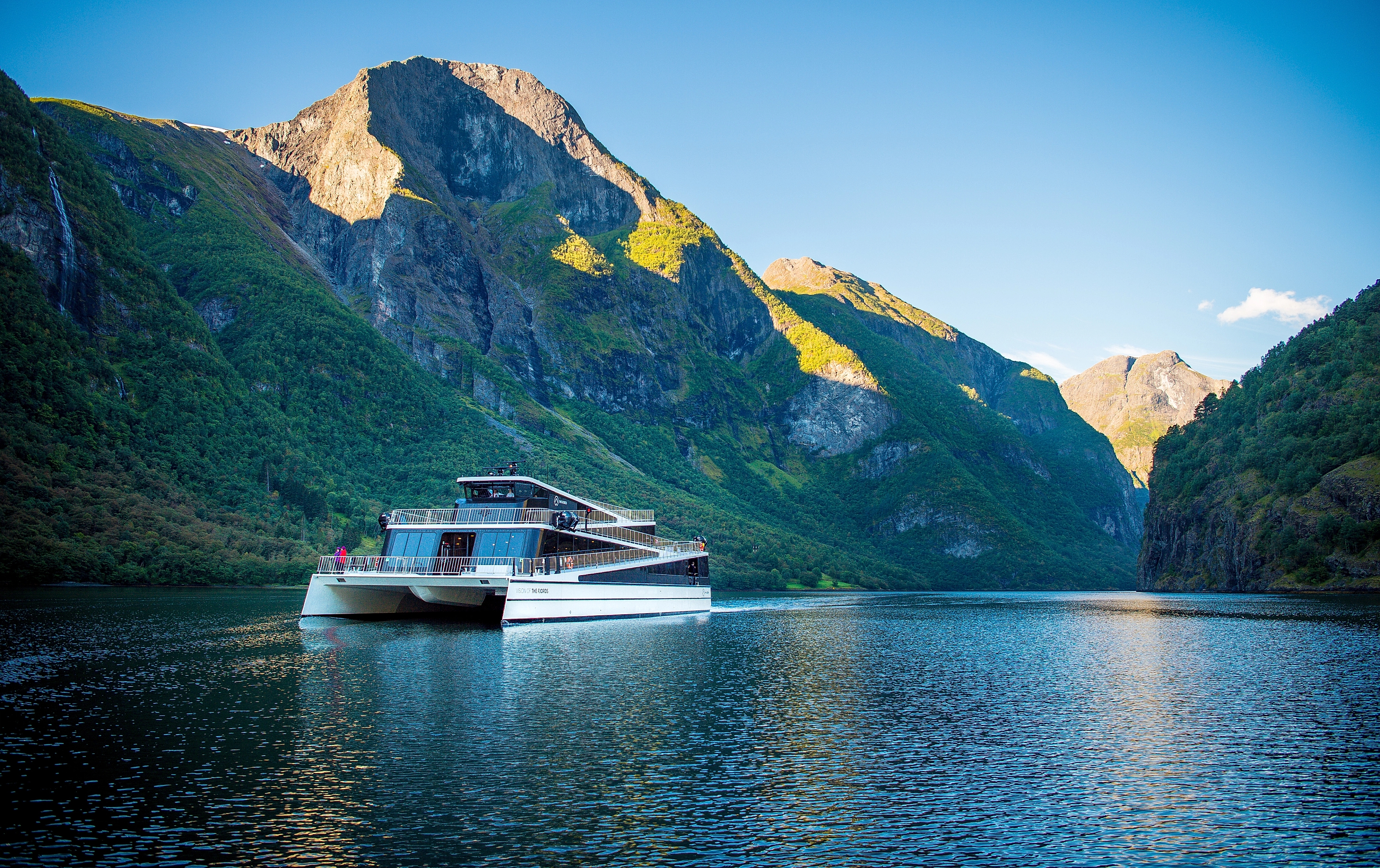 The ship Vision of the Fjords sailing between high mountains on a sunny summer day in Fjord Norway