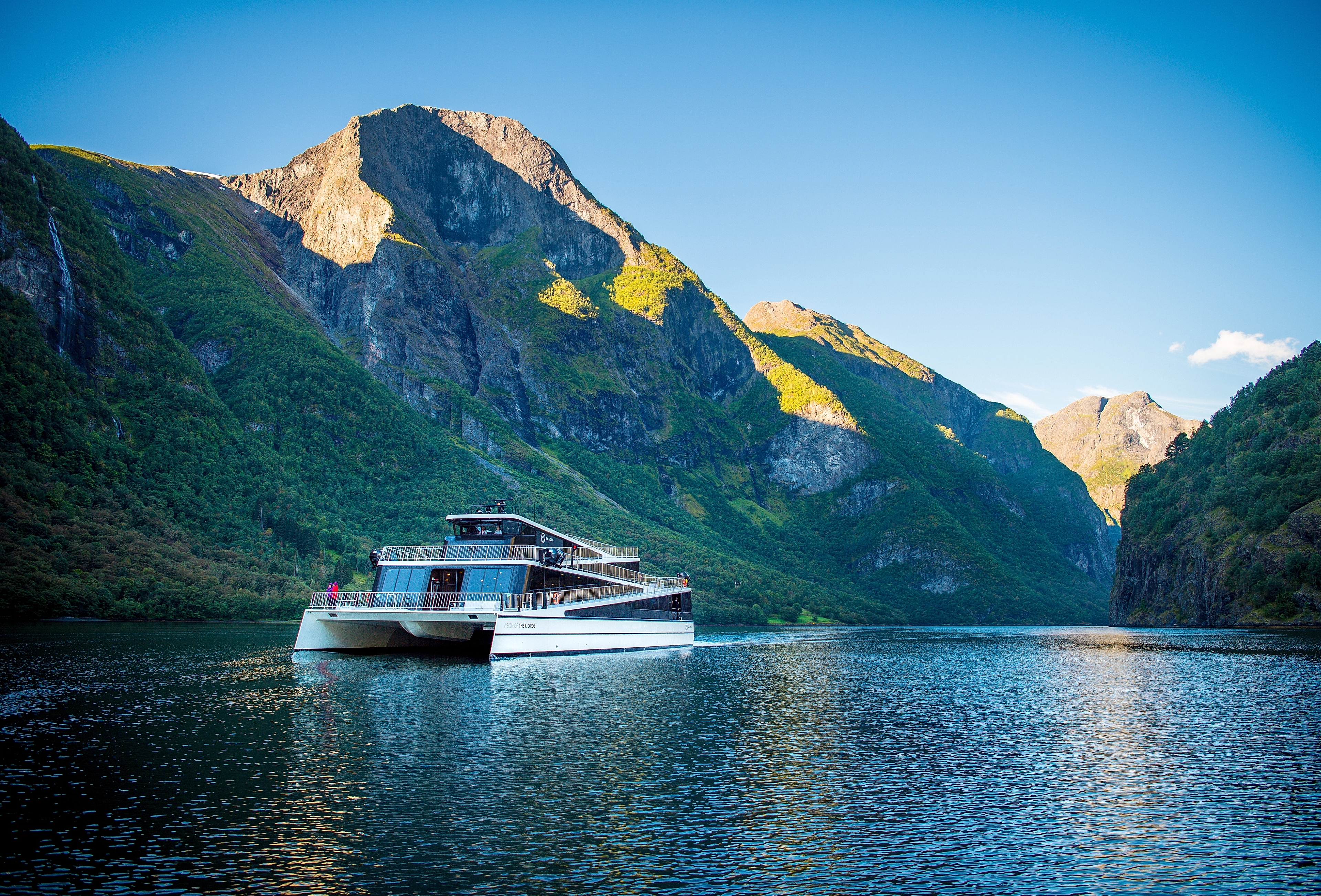 The ship Vision of the Fjords sailing between high mountains on a sunny summer day in Fjord Norway