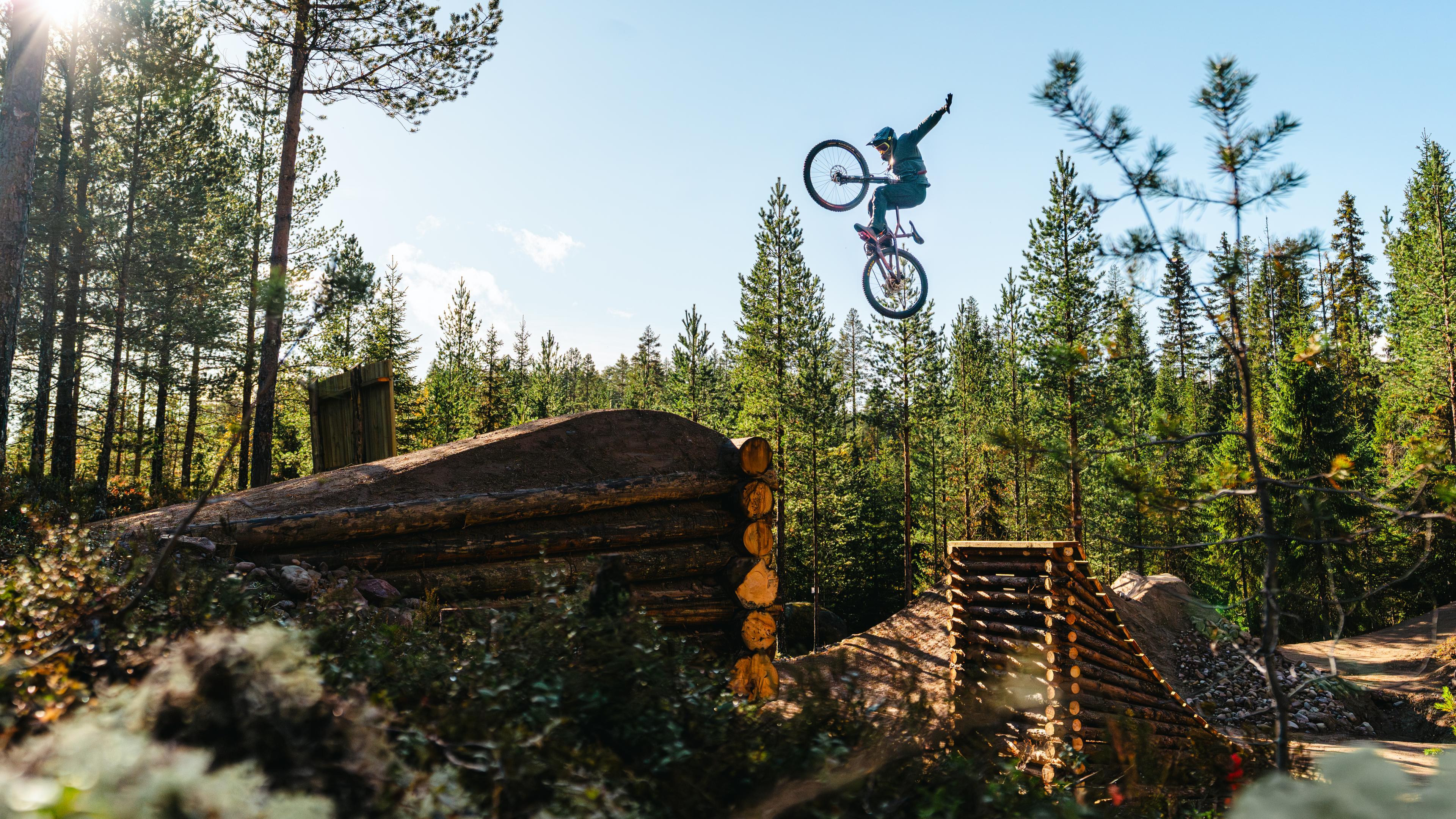A young boy jumping off a ramp with a mountain bike.