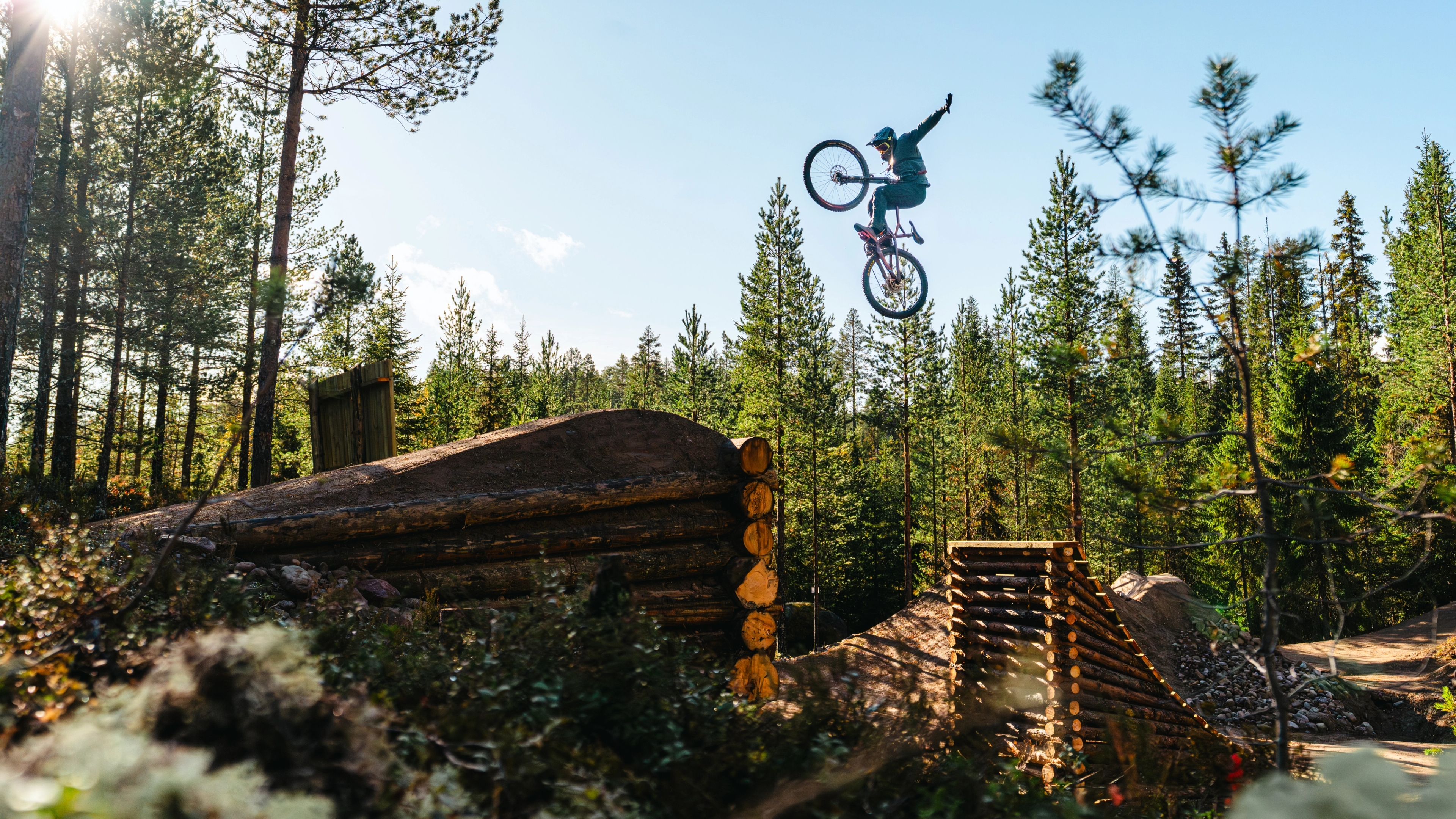 A young boy jumping off a ramp with a mountain bike.
