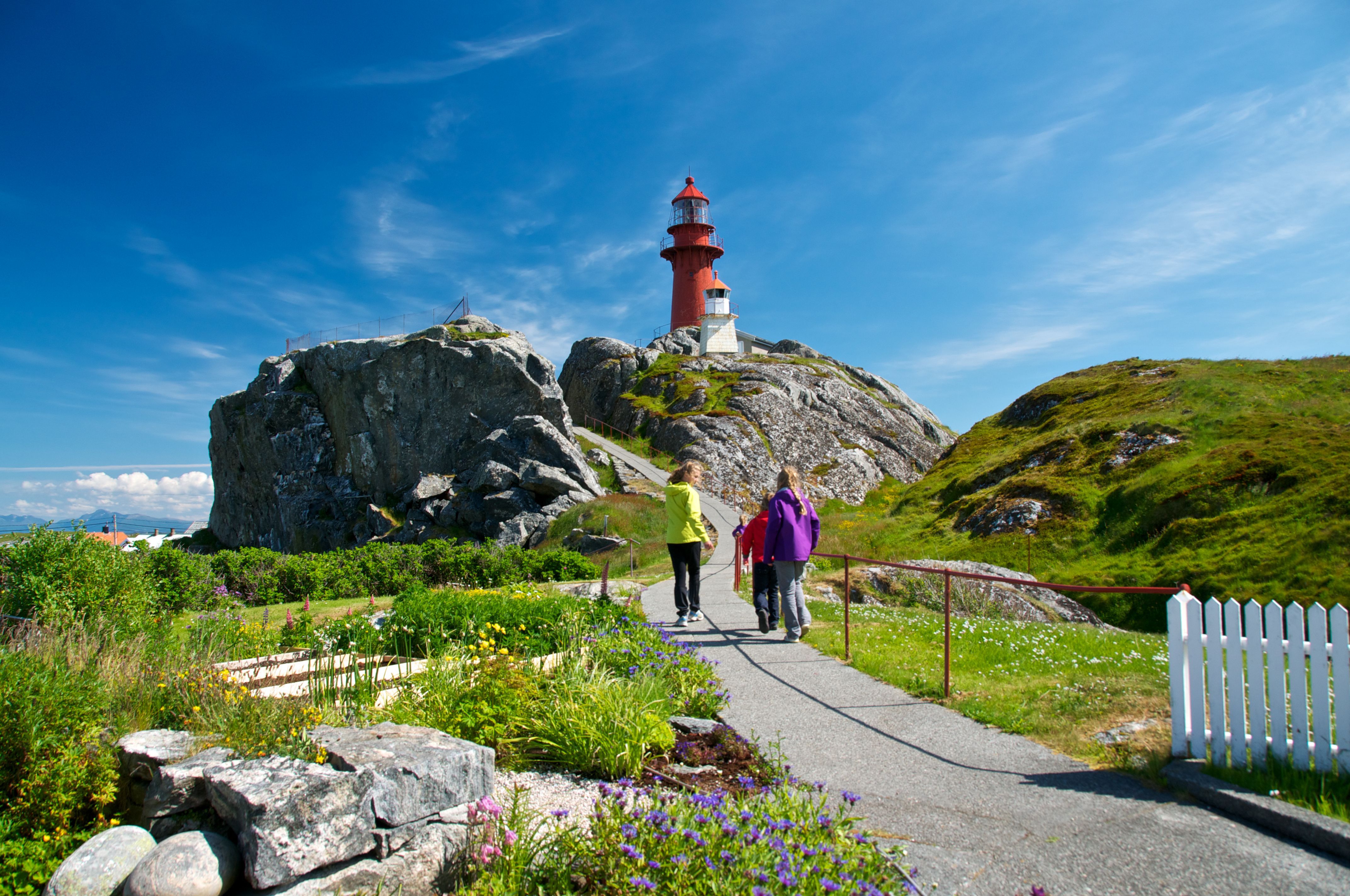 Personer går tur ved Ona fyr i havgapet nord for Ålesund, Norge.