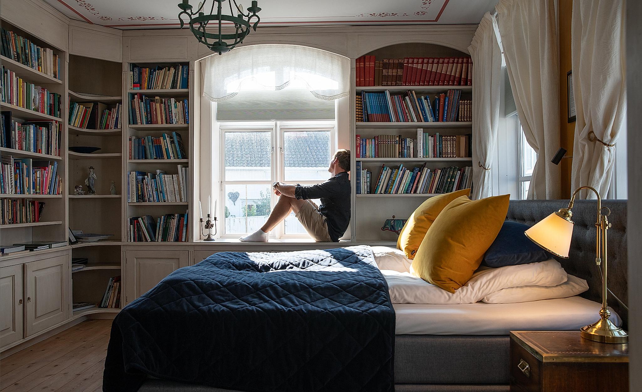 A person sitting on a bed in Det lille hotel in Risør, Southern Norway