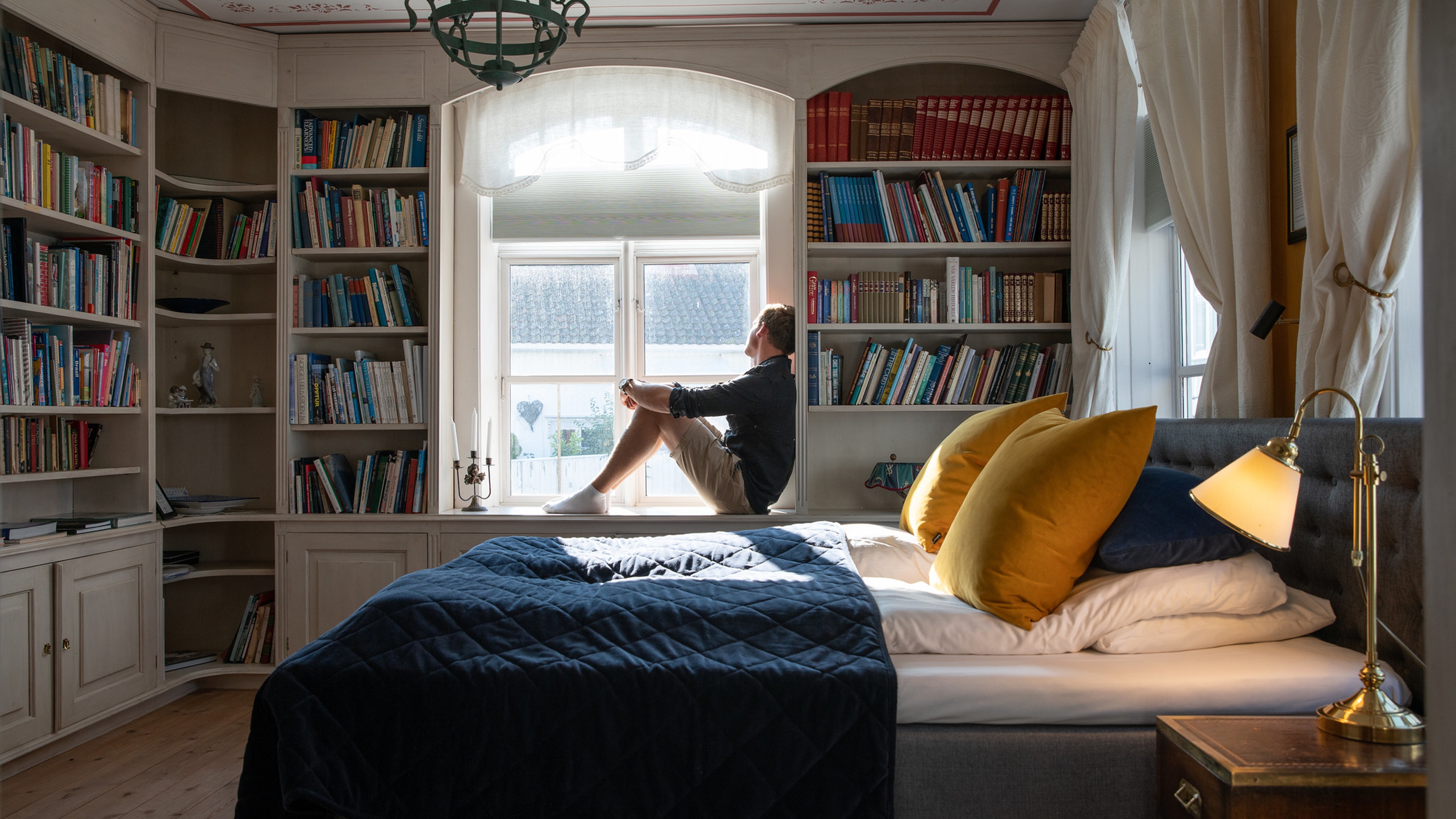 A person sitting on a bed in Det lille hotel in Risør, Southern Norway
