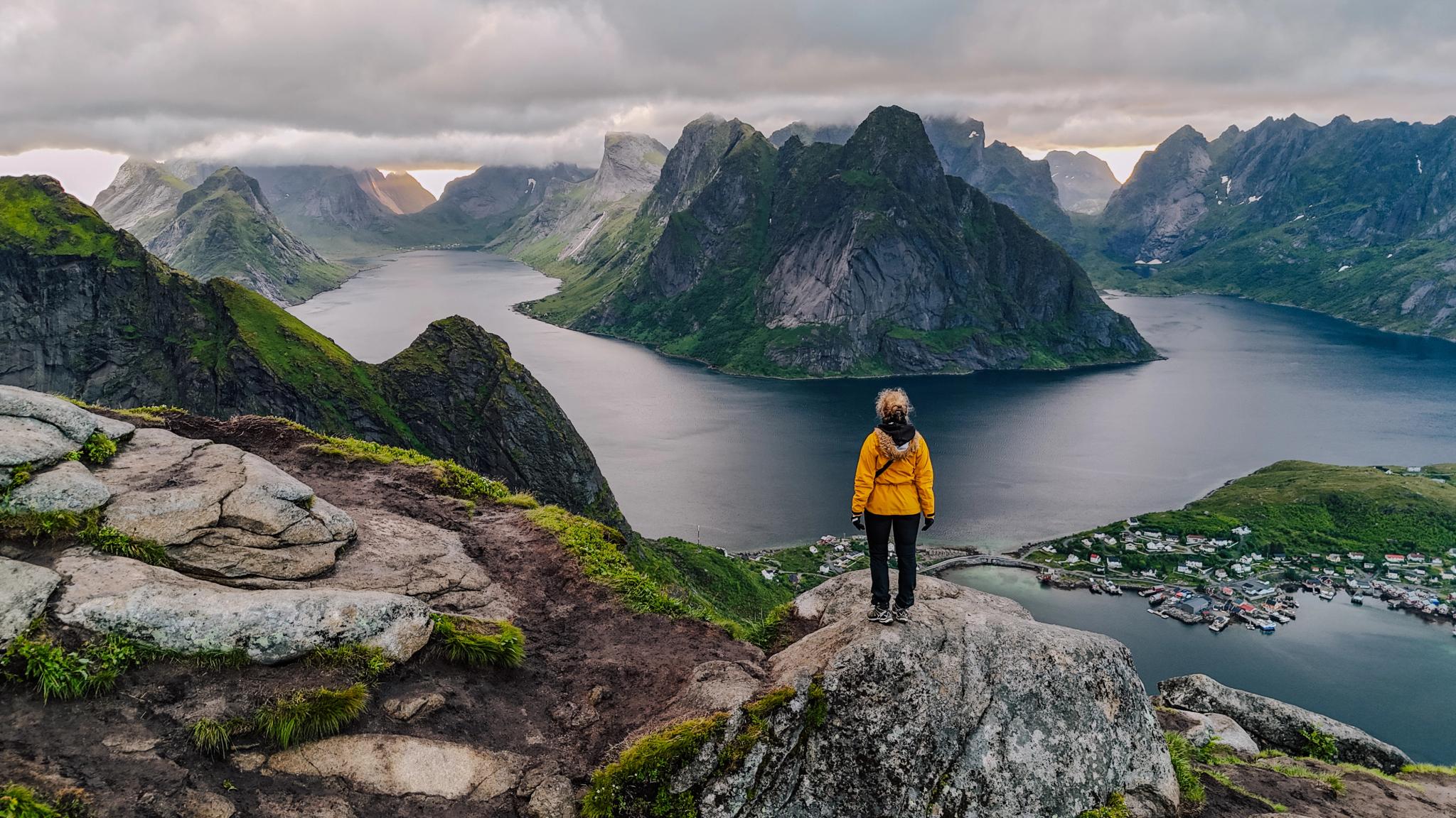 A person standing on top of the Reinebringen mountain in Lofoten.