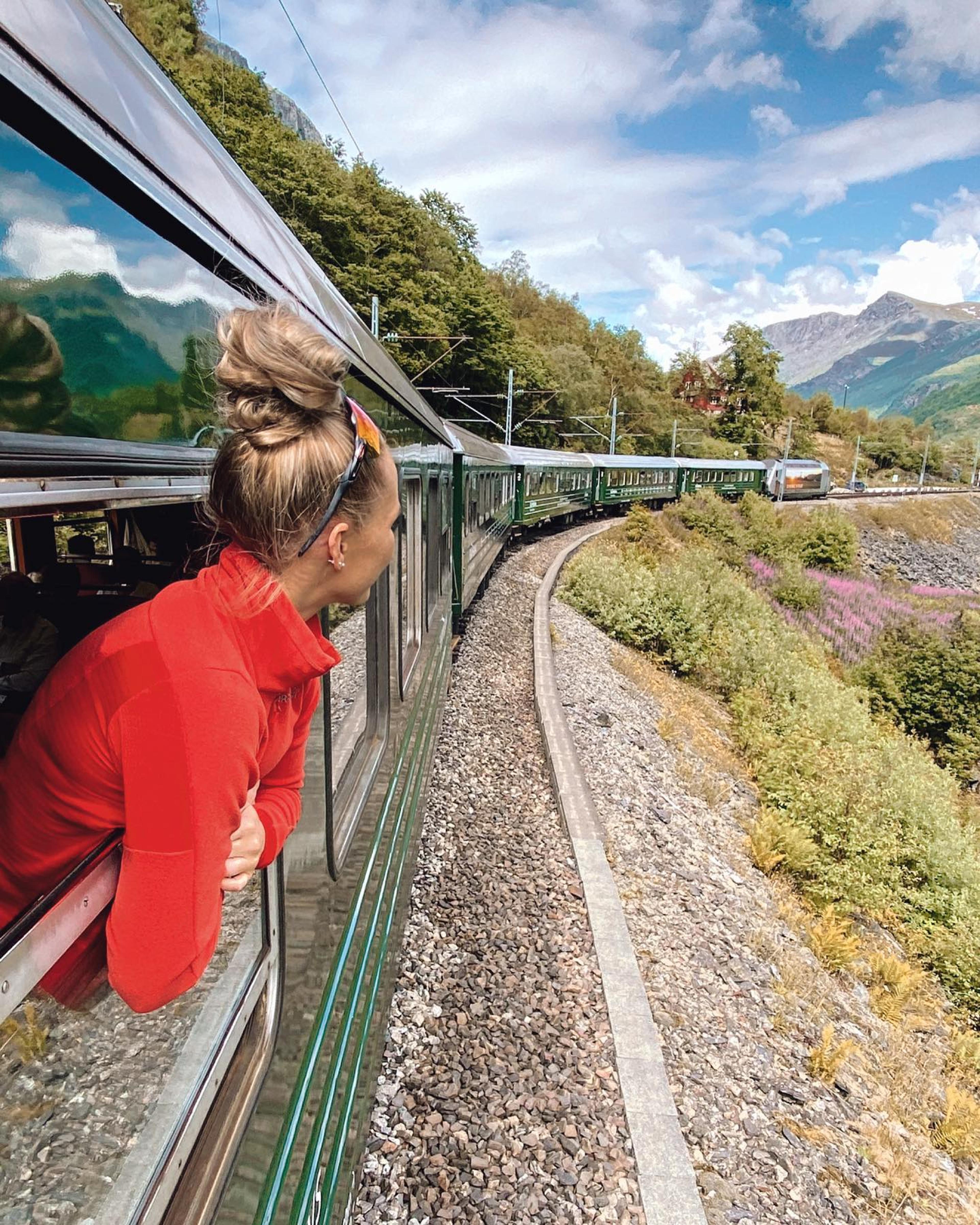 Person looking out train window at mountains
