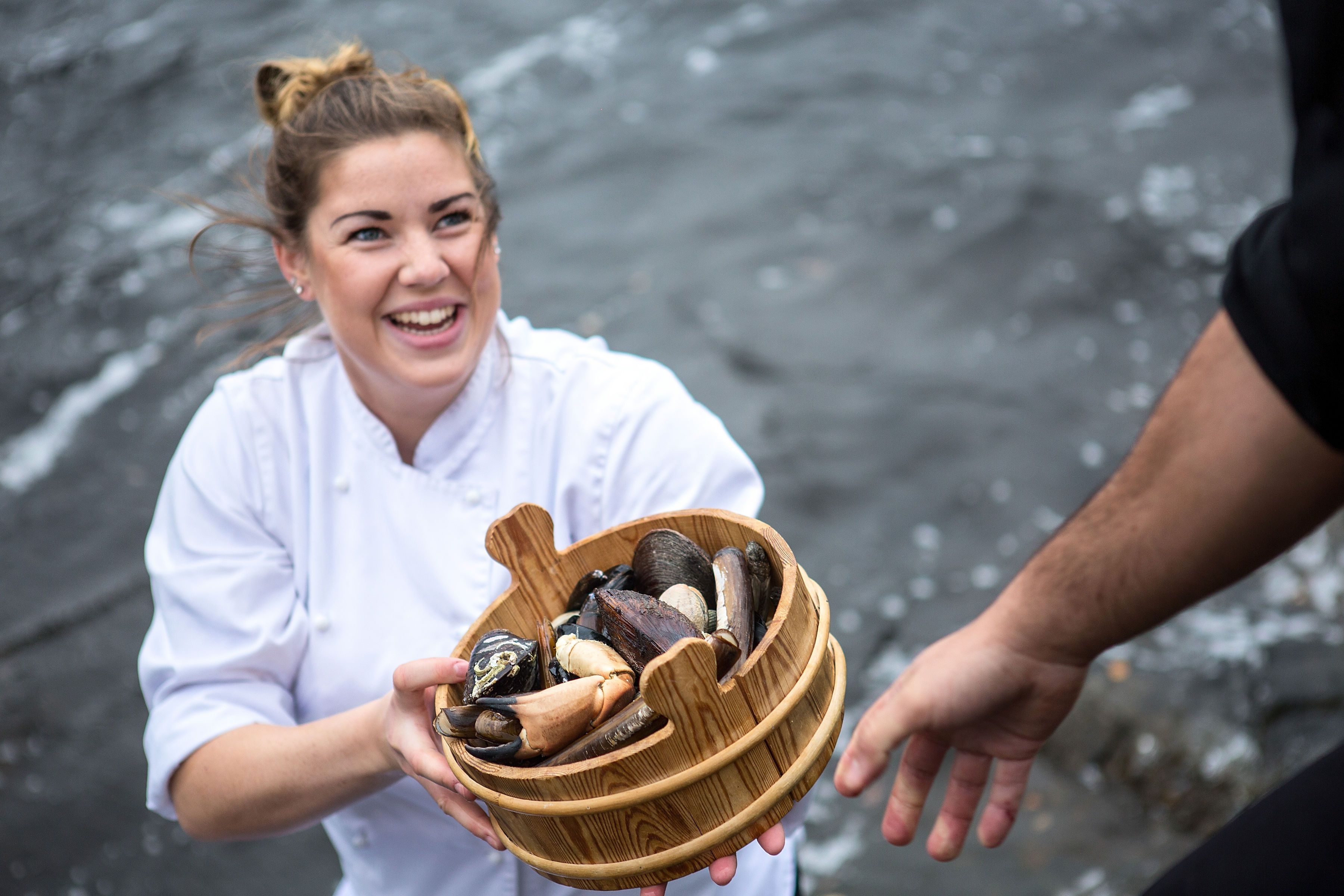 A renowned chef holding a bucket of fresh seafood from Fosen in Trøndelag