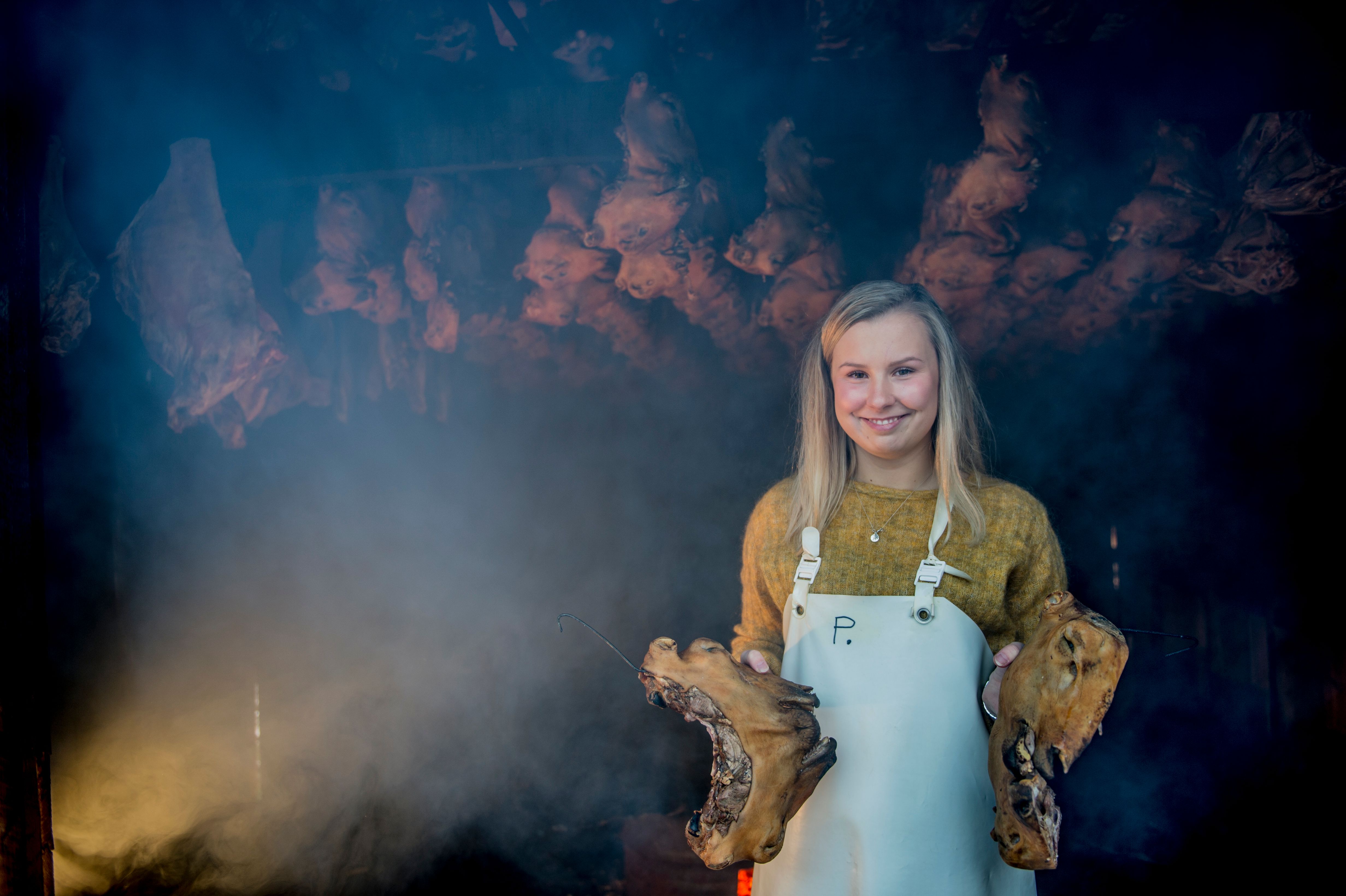 Woman holding two sheep heads at Smalahovetunet in Voss, Fjord Norway