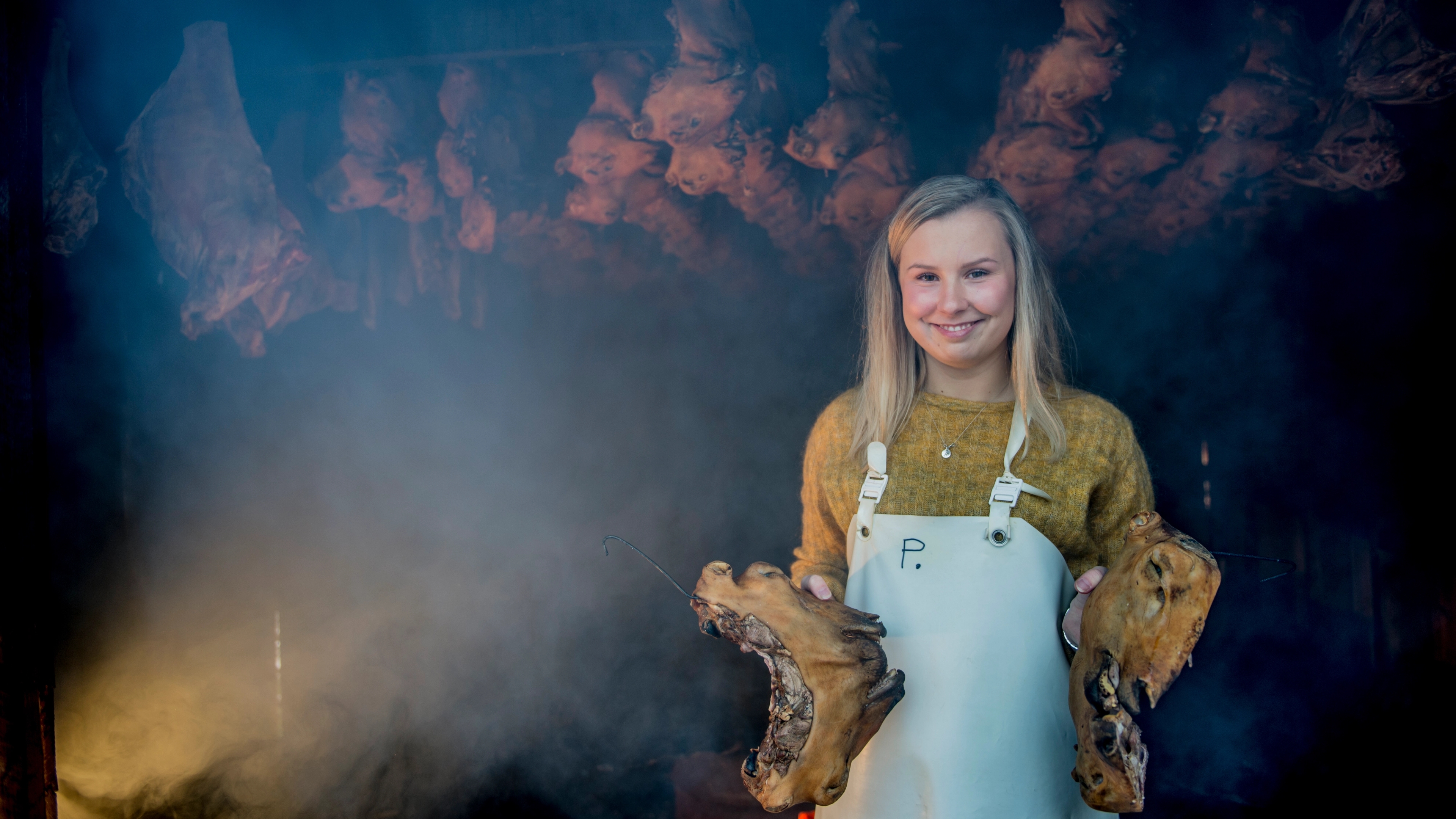 Woman holding two sheep heads at Smalahovetunet in Voss, Fjord Norway
