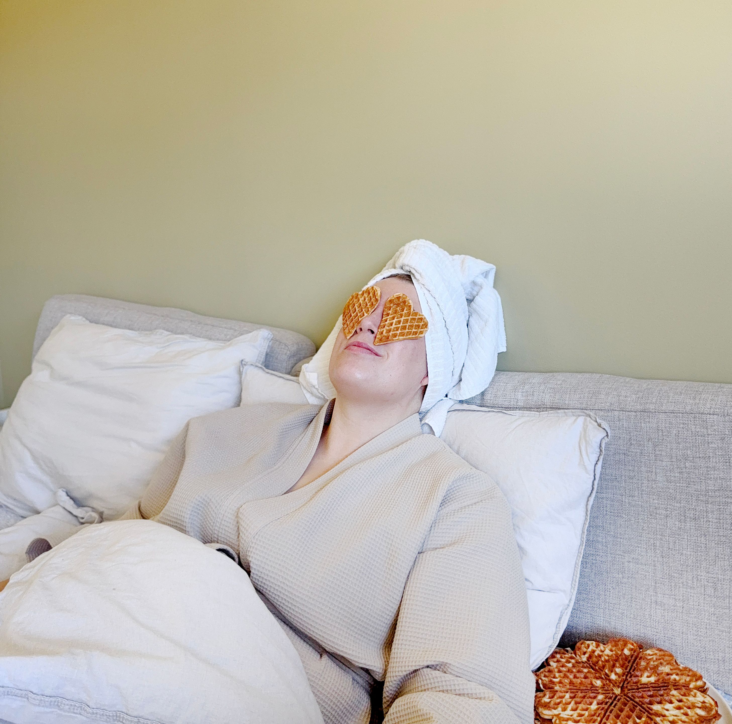 A woman laying in bed with waffles on her eyes. 
