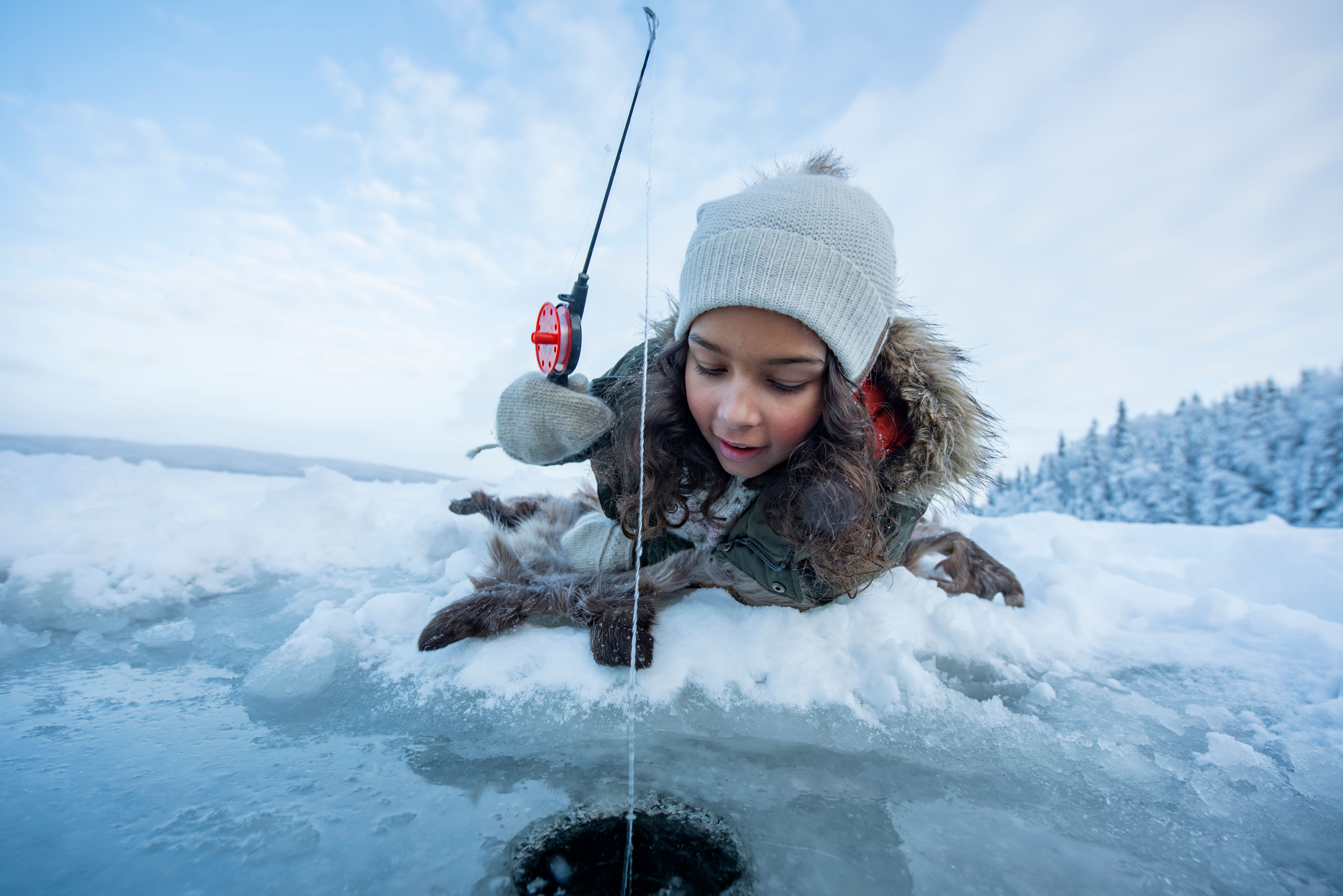 Girl ice fishing on a frozen lake in Namdalen, Norway