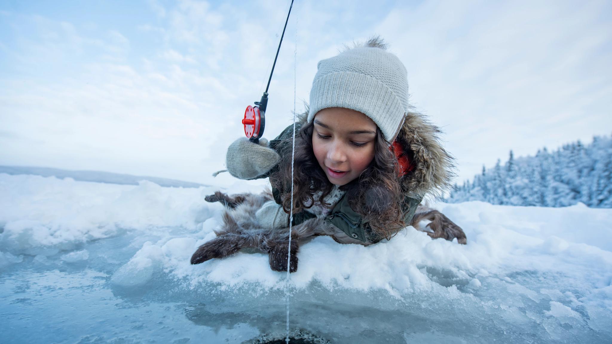 Girl ice fishing on a frozen lake in Namdalen, Norway