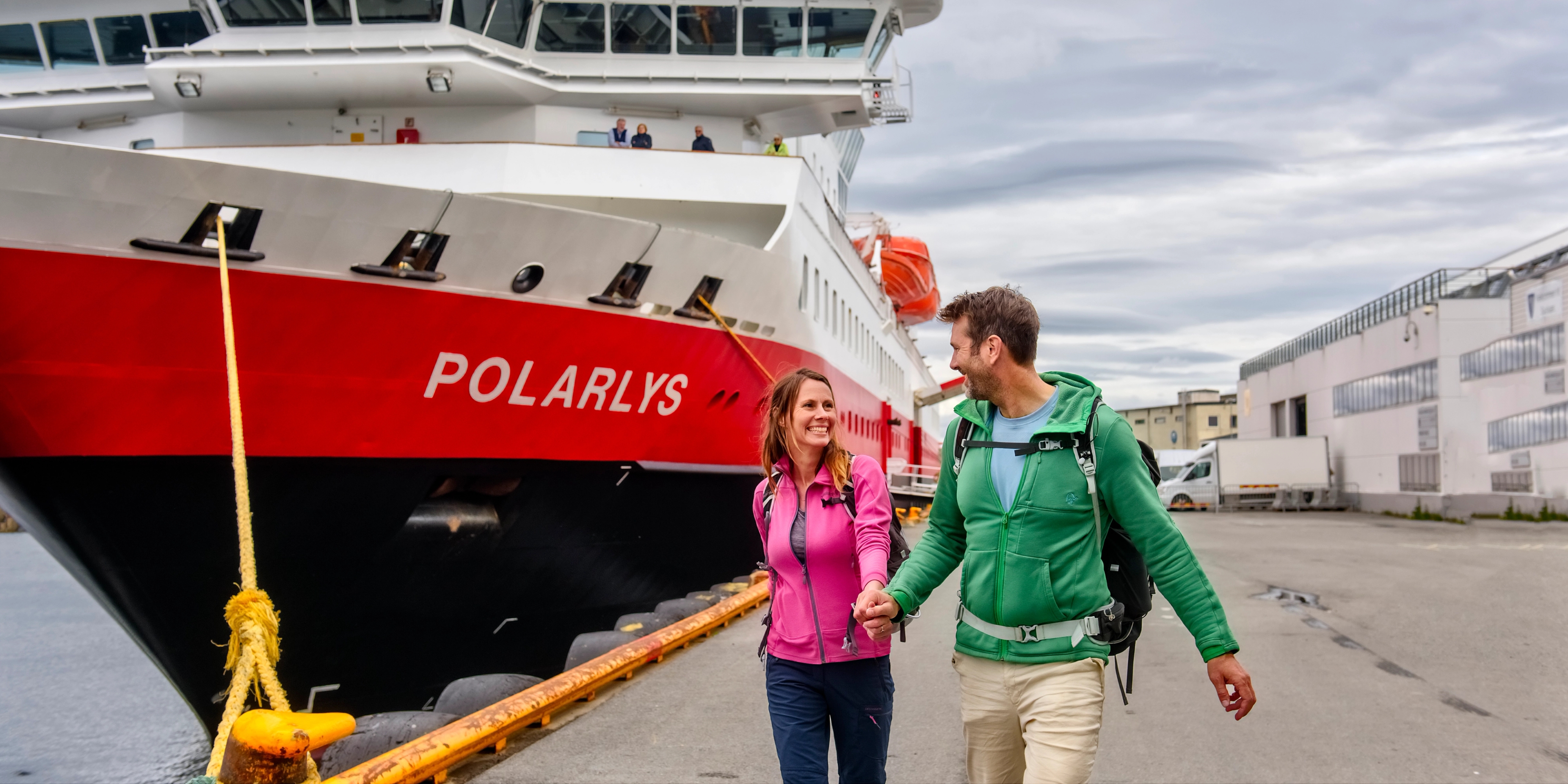 A smiling couple in front of the MS Polarlys Hurtigruten ship in Lofoten, Northern Norway