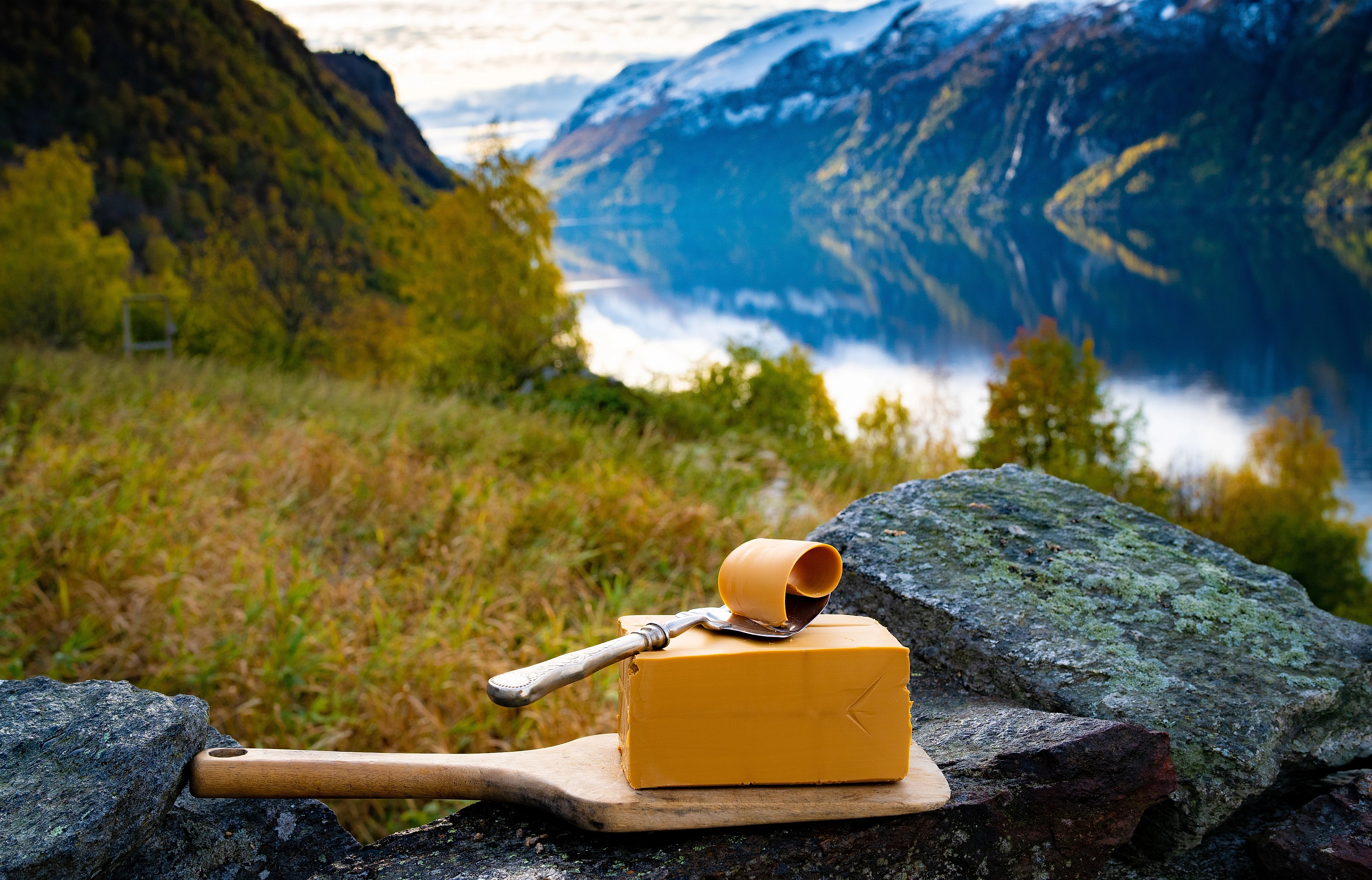 Norwegian brown cheese against a backdrop of mountains and a fjord