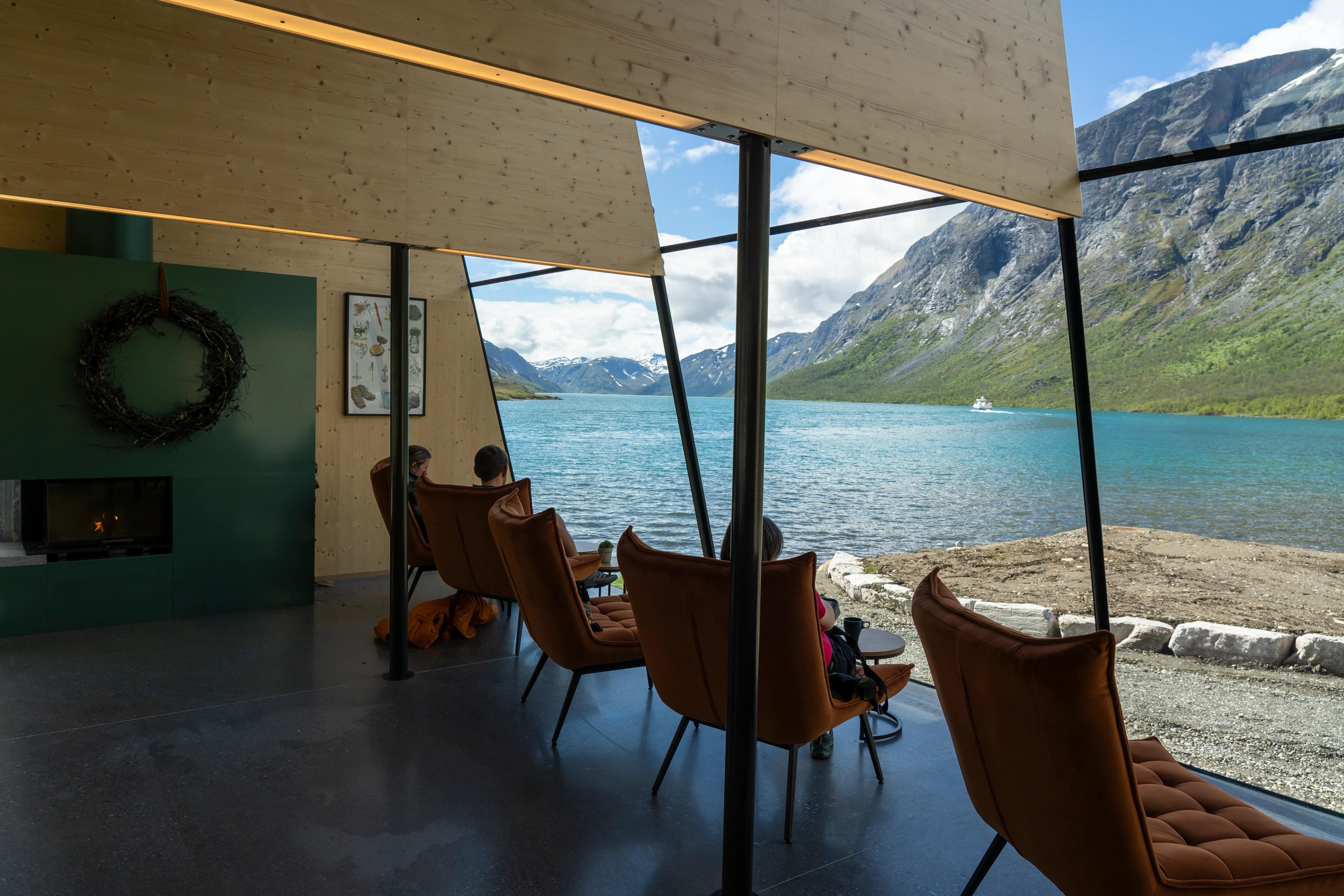 People sitting inside of Café Gjendeosen with view out to the Gjende lake.