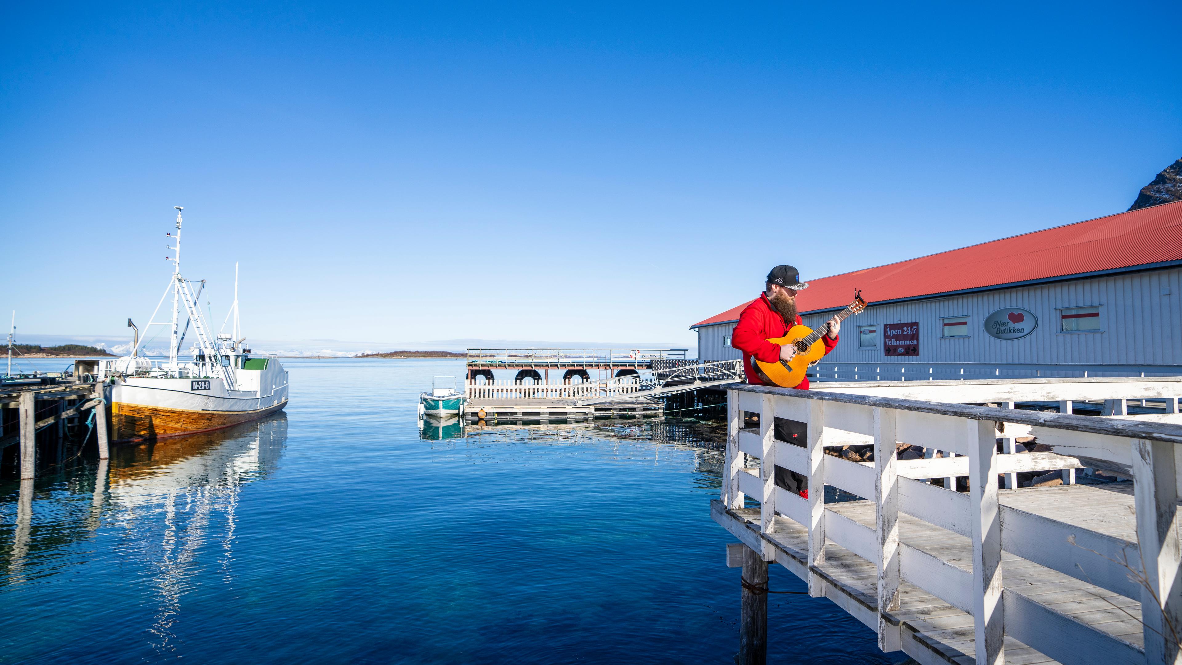 A man playing the guitar at in the harbour.