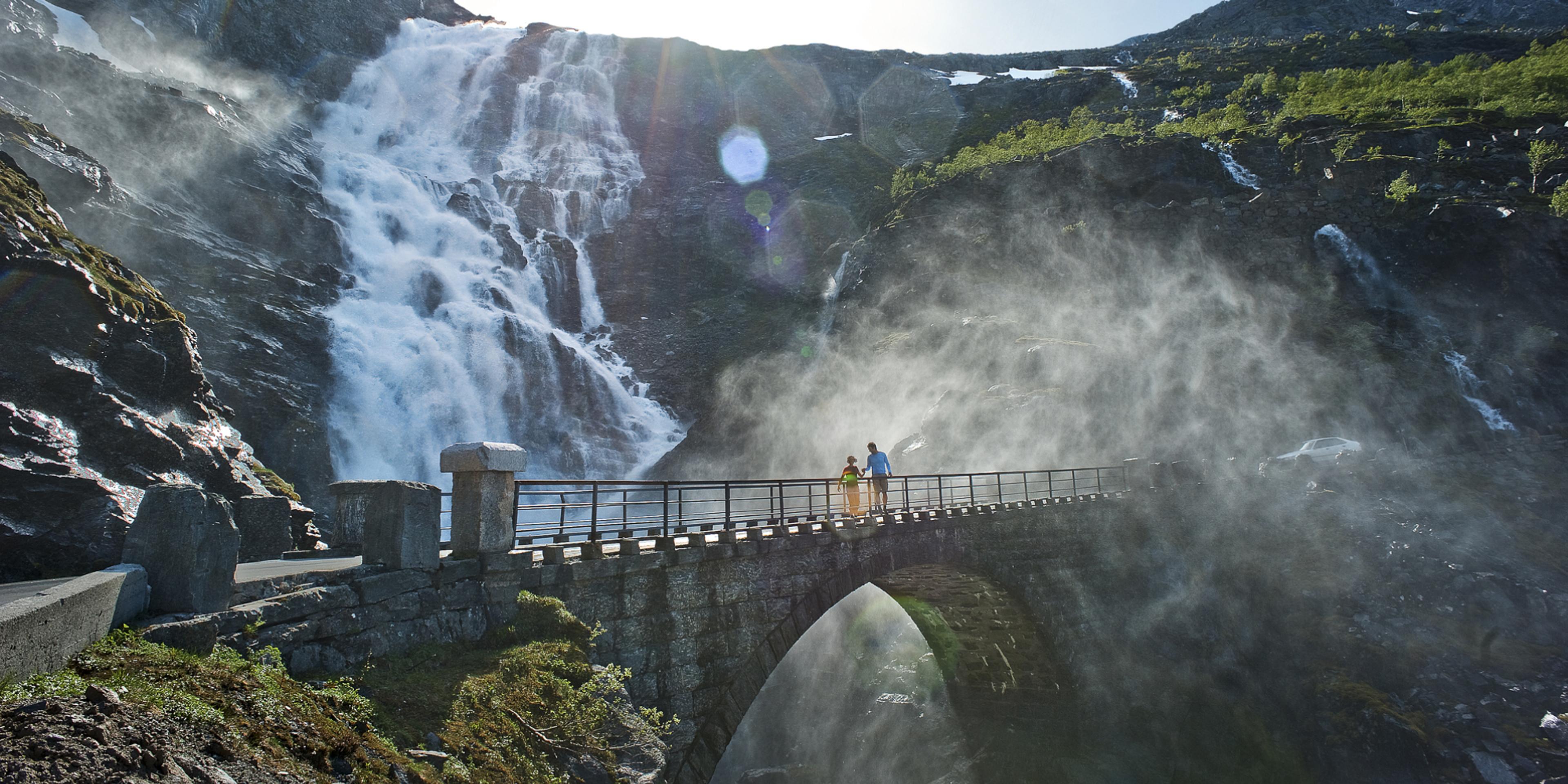 Two people running over a bridge at the Trollstigen road, in Rauma