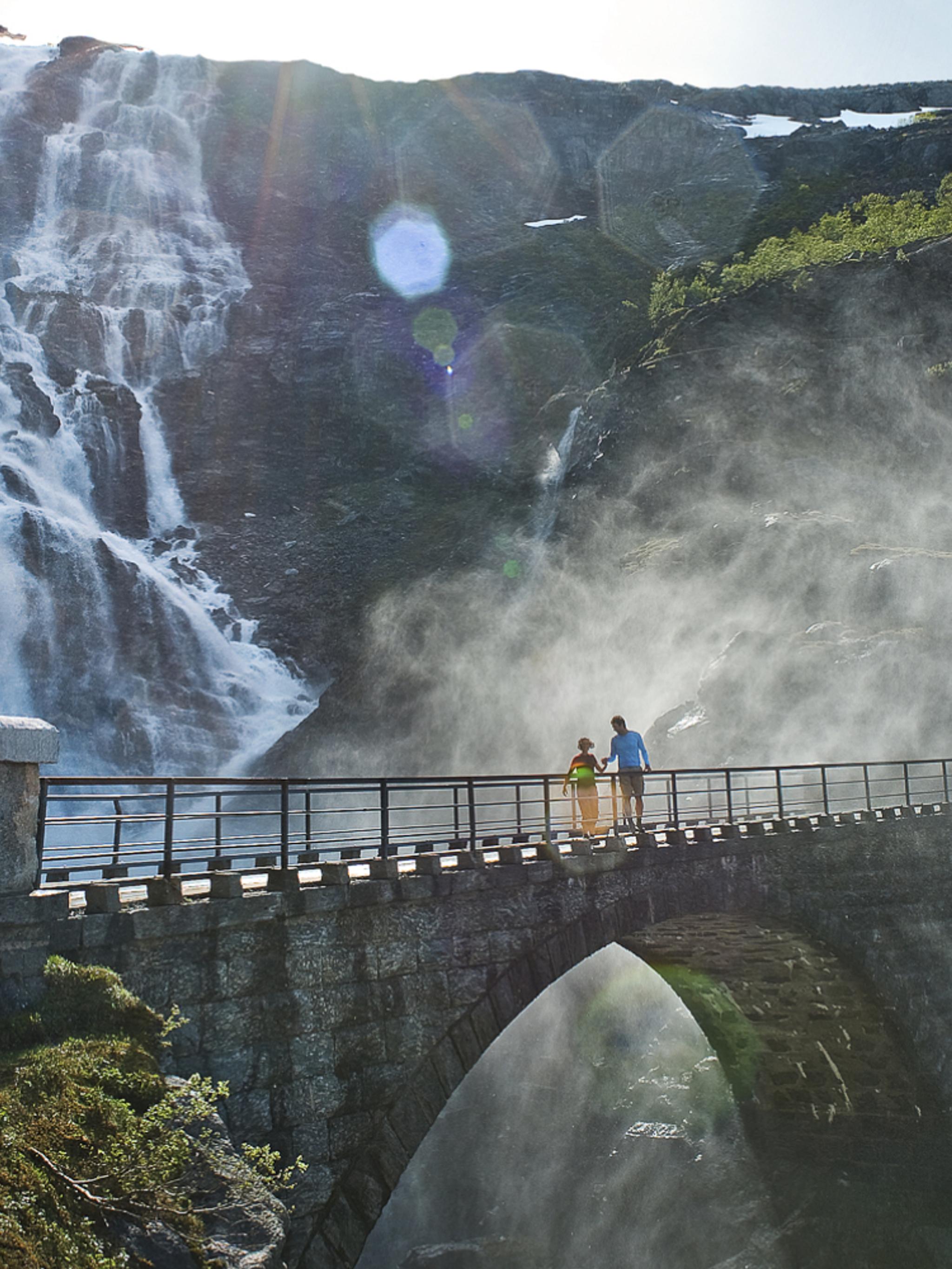 Two people running over a bridge at the Trollstigen road, in Rauma