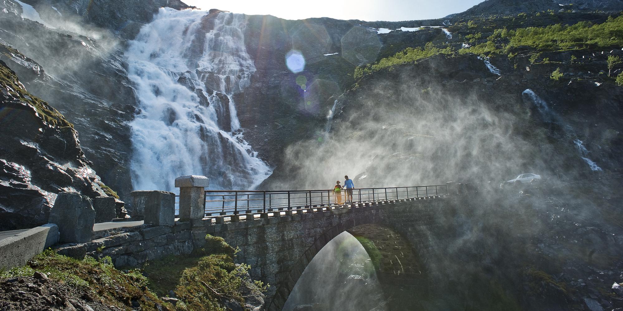 Two people running over a bridge at the Trollstigen road, in Rauma