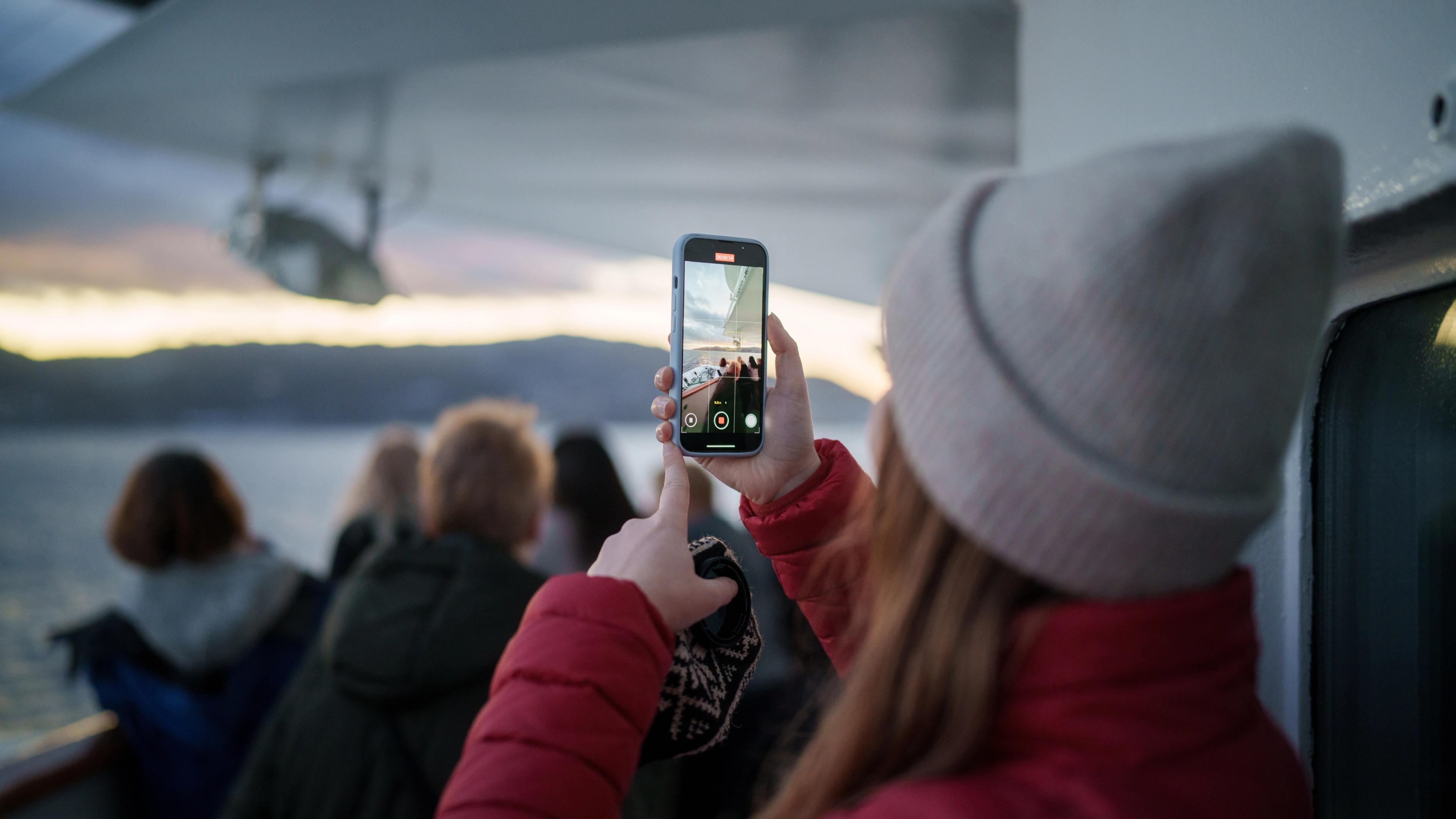Woman filming a video on deck at Hurtigruten