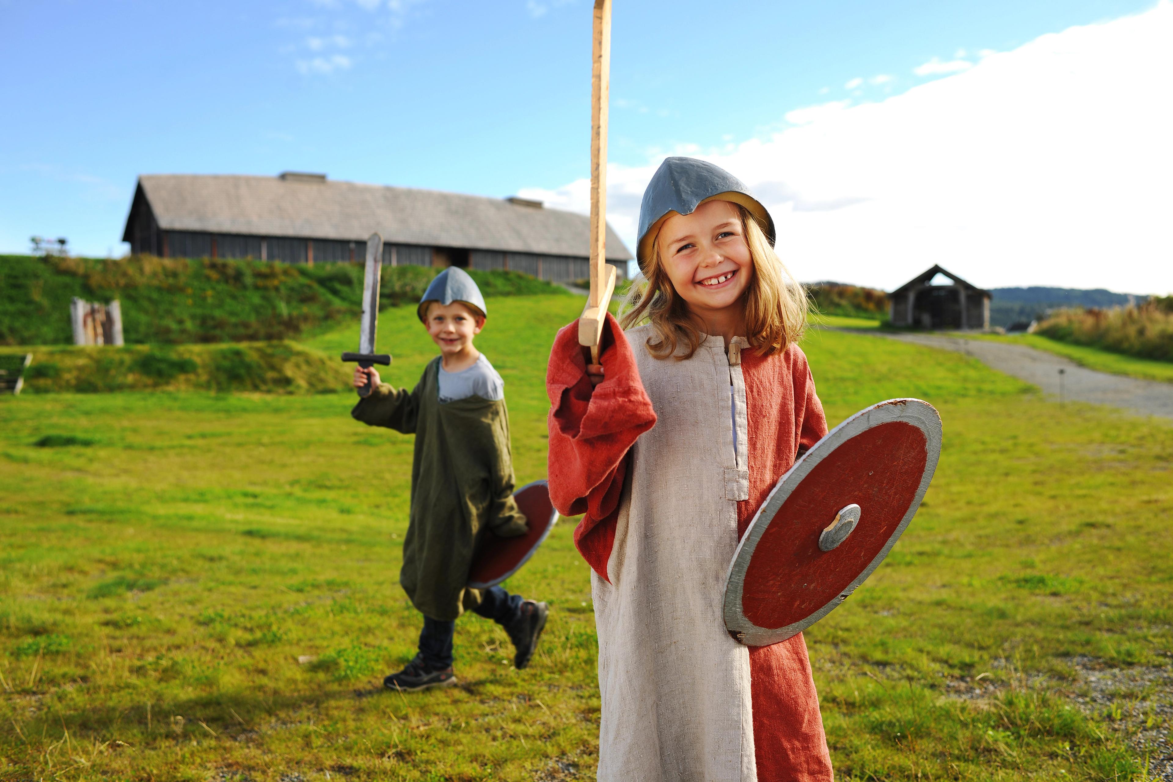 Children dressed as Vikings in front of a longhouse at Stiklestad in Trøndelag, Norway