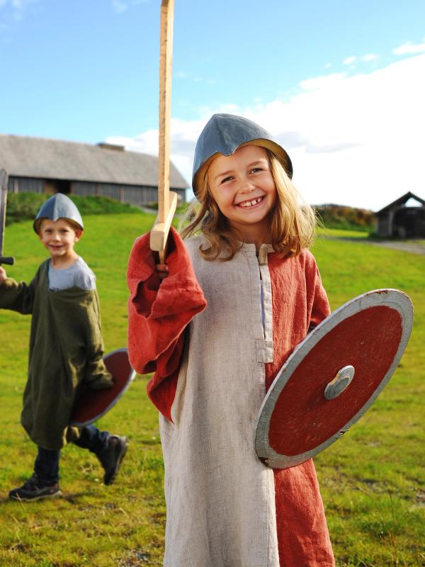 Children dressed as Vikings in front of a longhouse at Stiklestad in Trøndelag, Norway