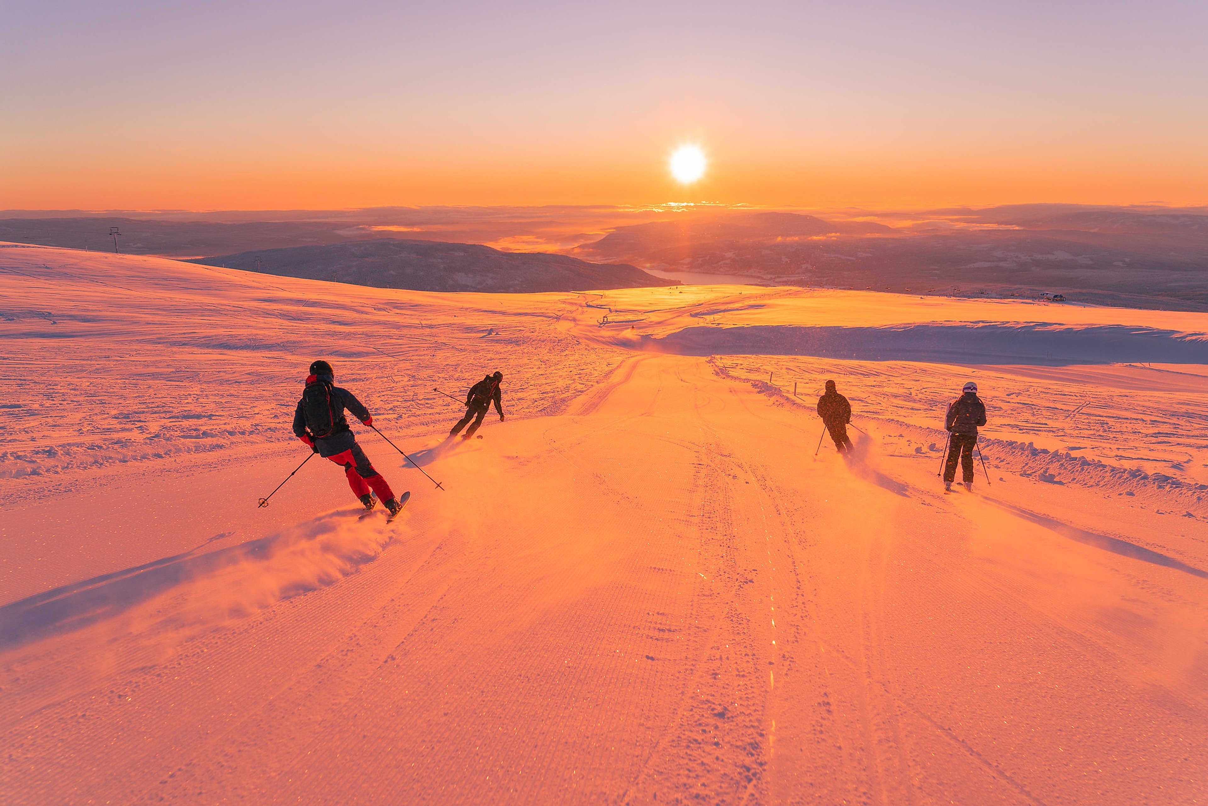 People skiing at Norefjell Ski Resort in sunset, winter