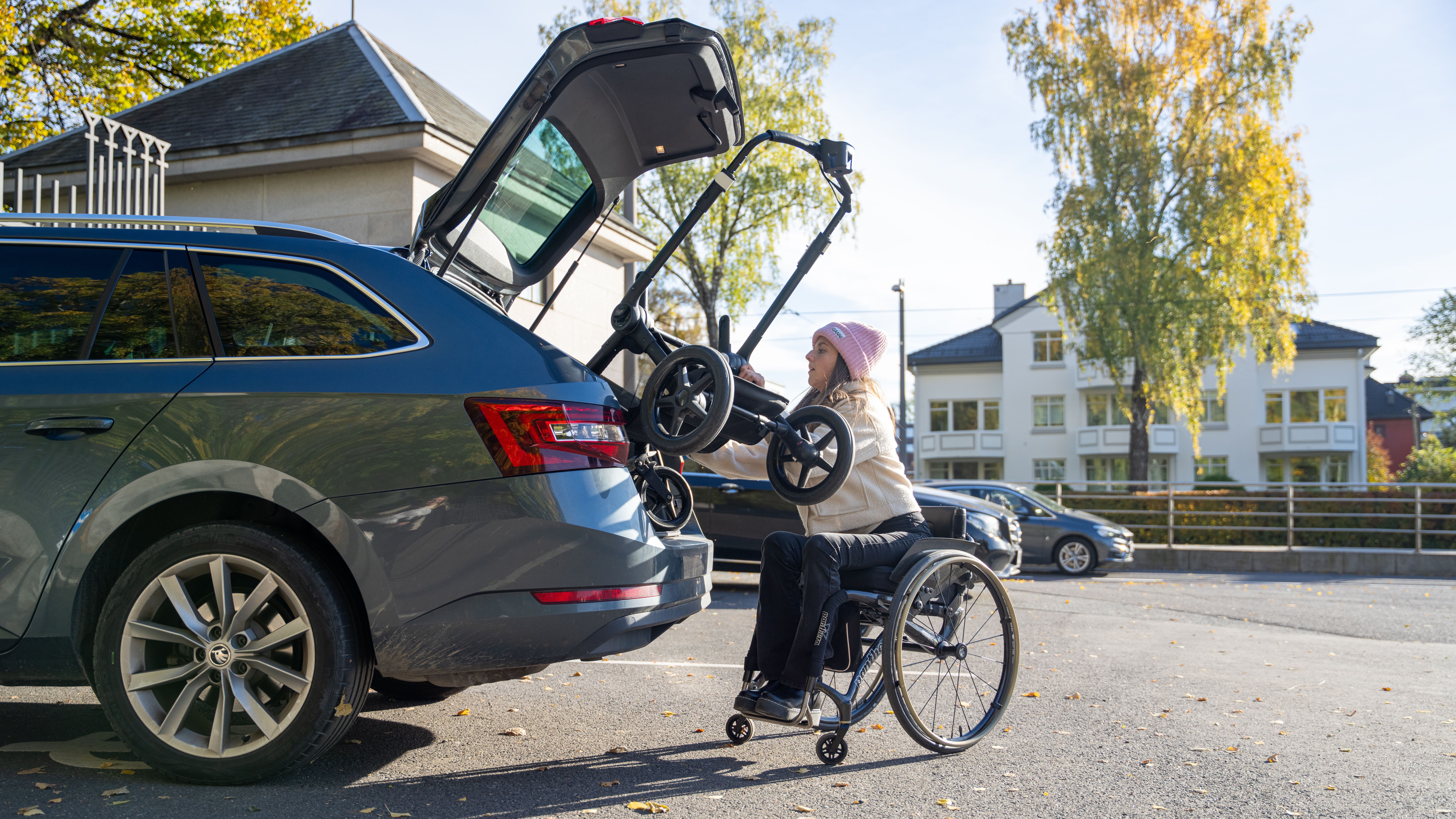 A woman in wheelchair lifts pram into her car