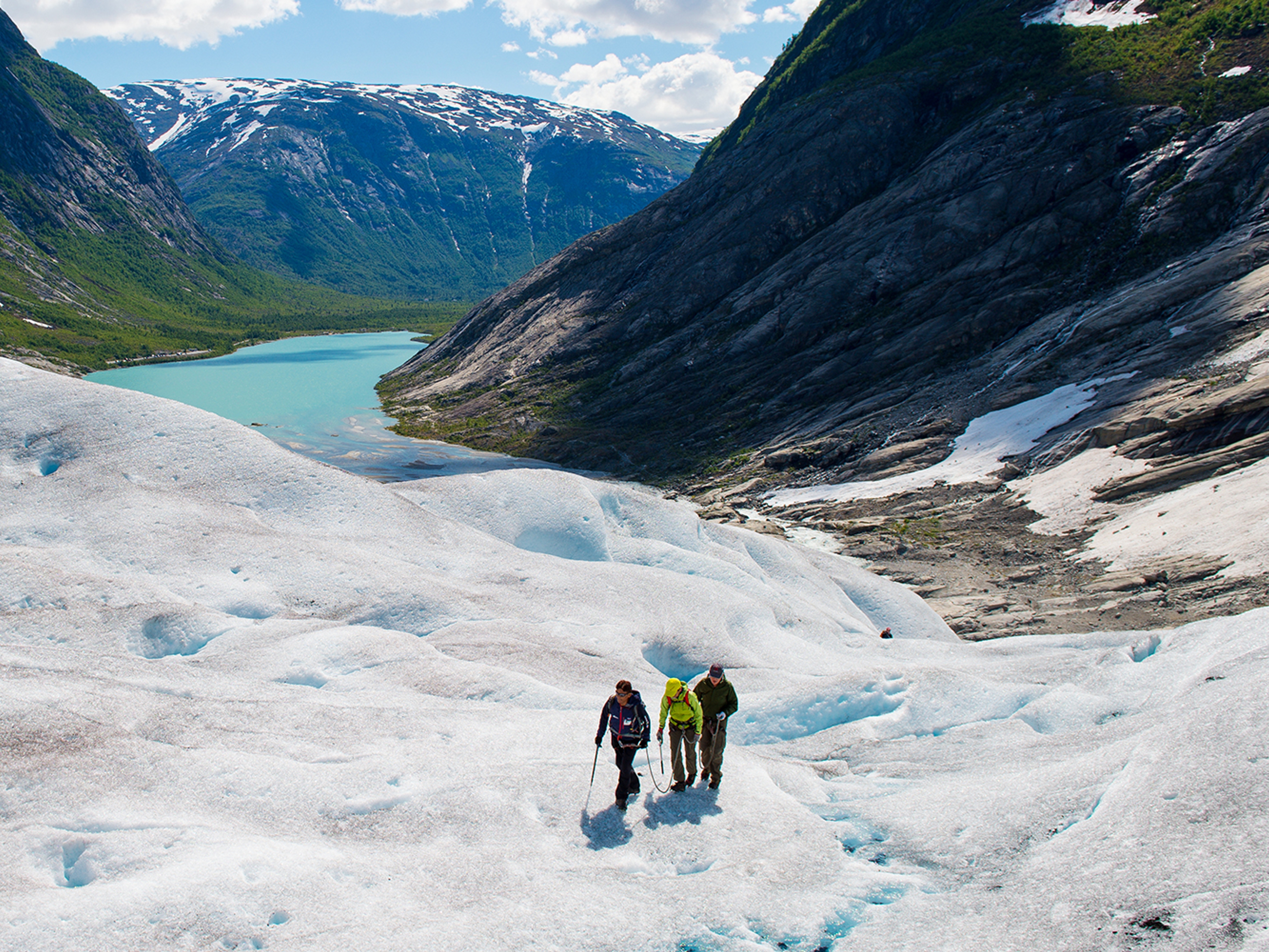 Three people hiking on the Nigardsbreen glacier in Fjord Norway