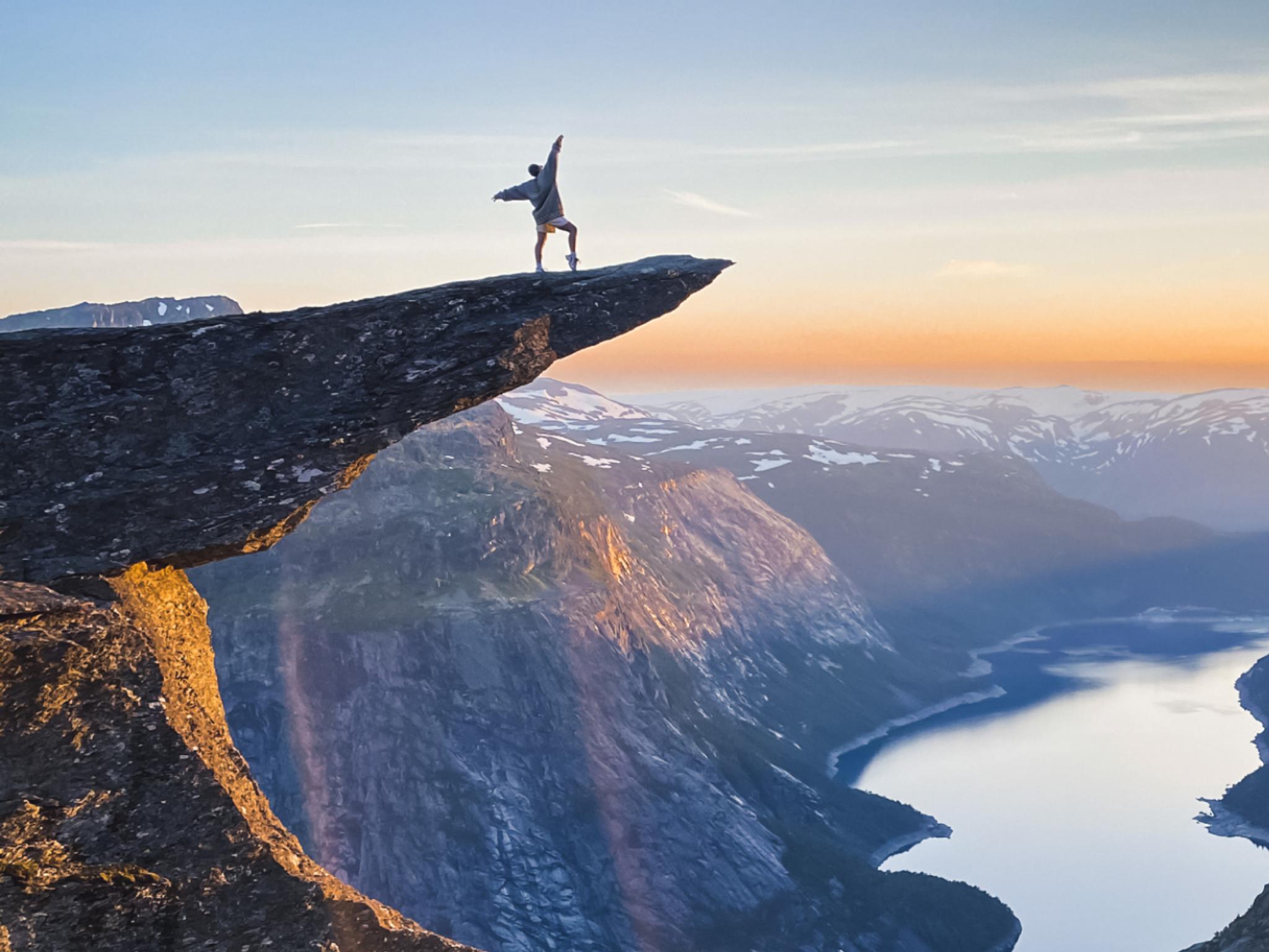 Person standing on Trolltunga in Odda, Fjord Norway