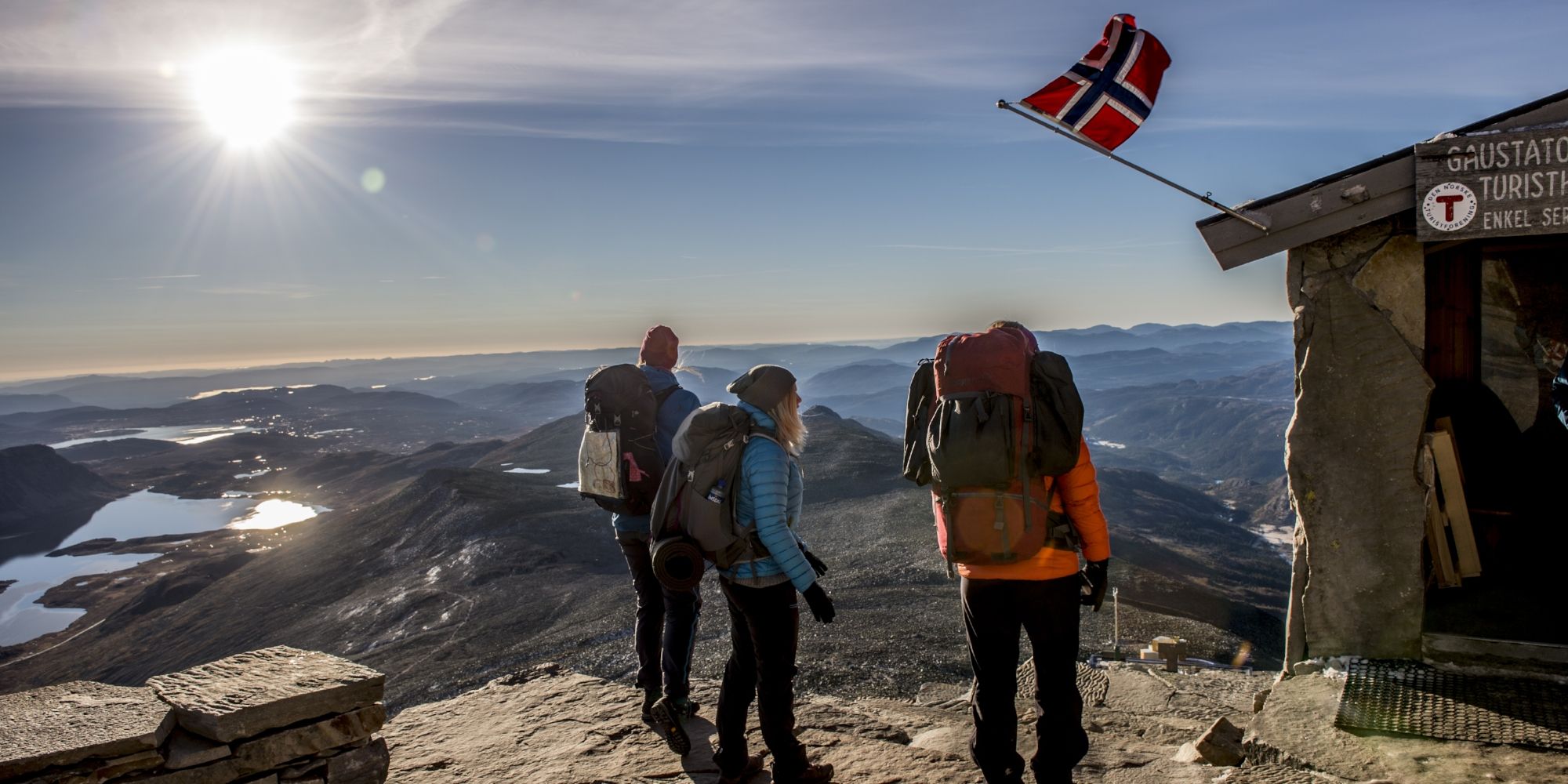 En grupp människor njuter av utsikten från Gaustatoppen en solig dag