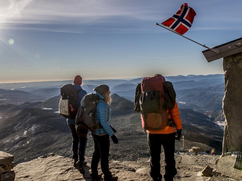 En grupp människor njuter av utsikten från Gaustatoppen en solig dag