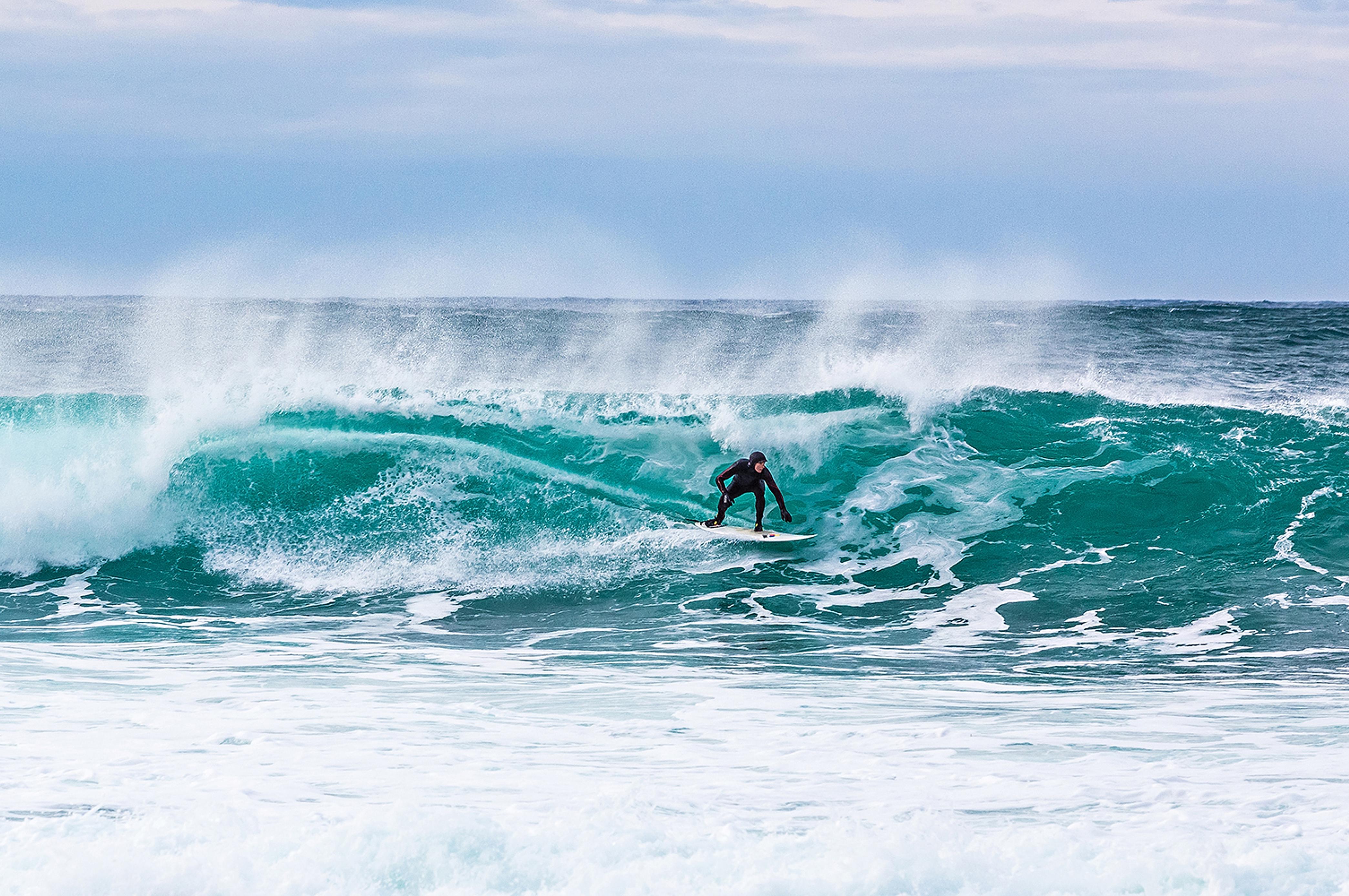En man surfar på en våg i Unstad i Lofoten, norra Norge