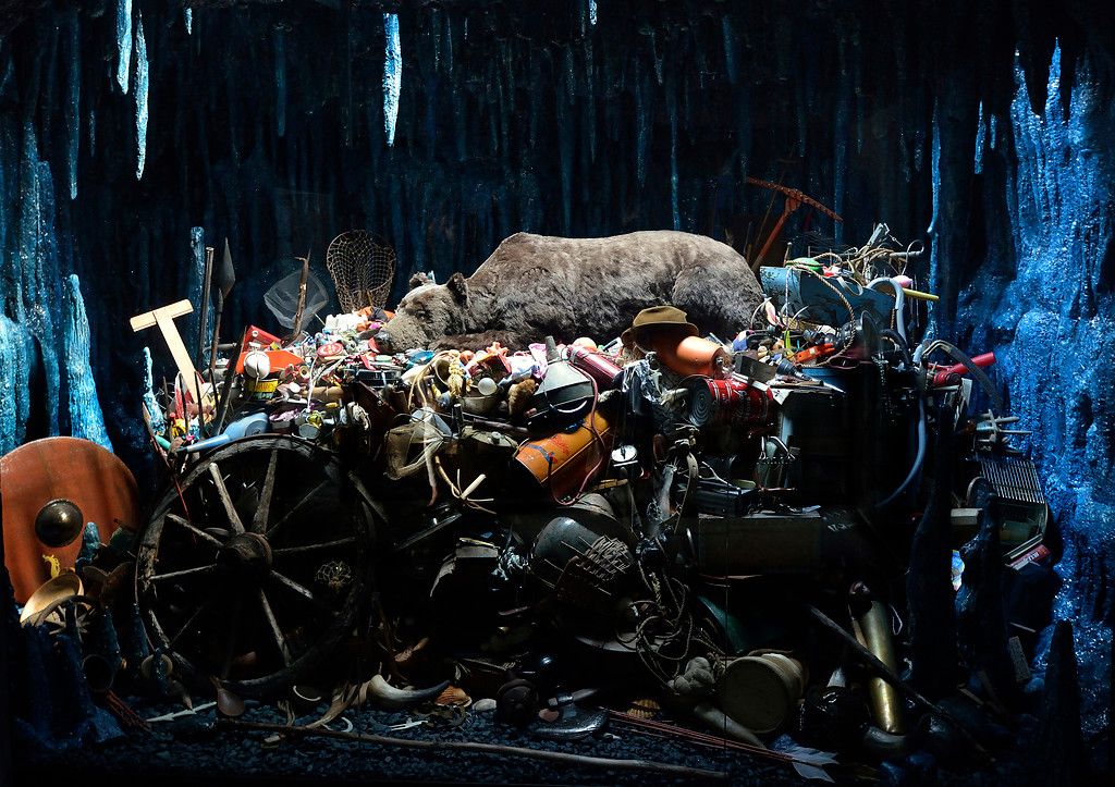 A bear sleeping upon a pile of human artifacts