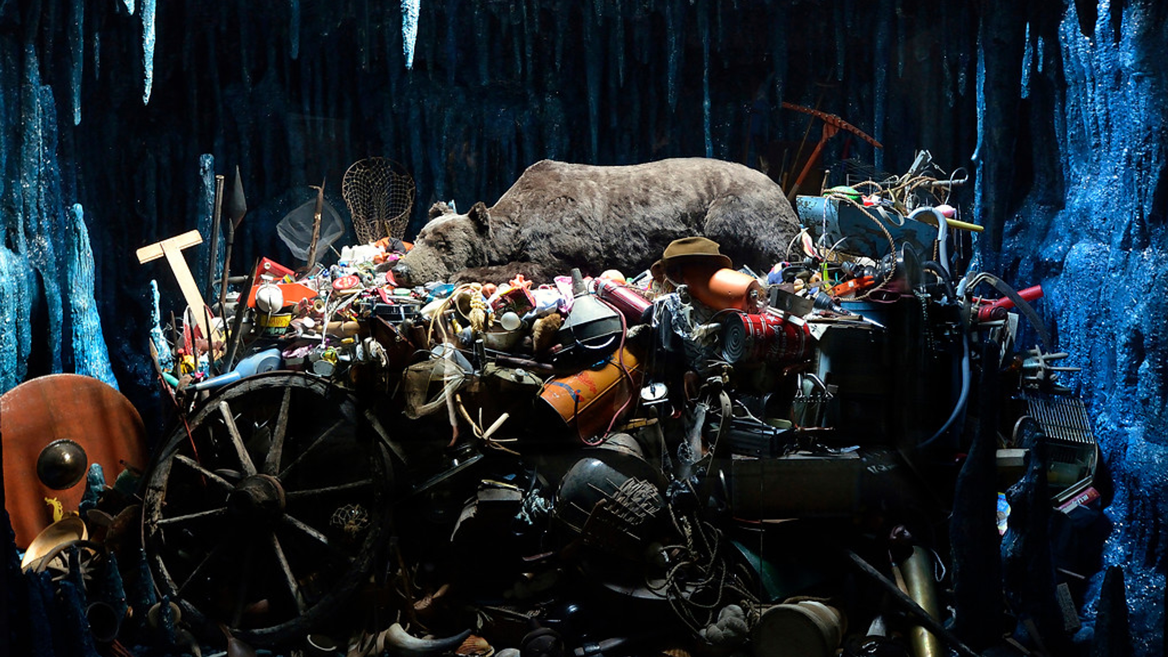 A bear sleeping upon a pile of human artifacts