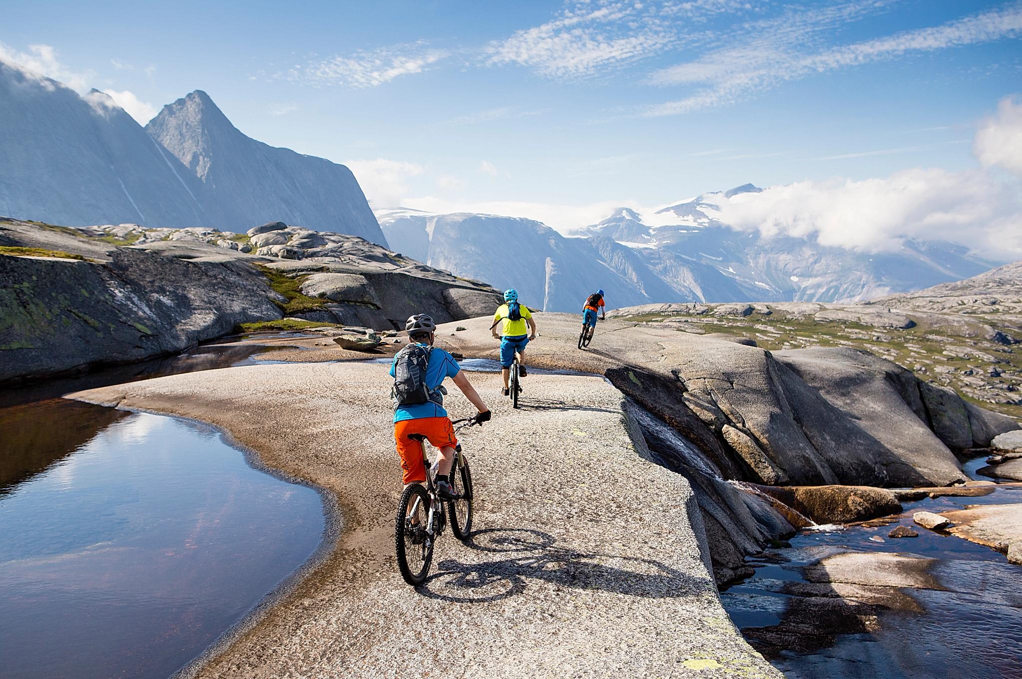 Drei Mountainbiker in Narvik, Nordnorwegen, umgeben von hohen Bergen