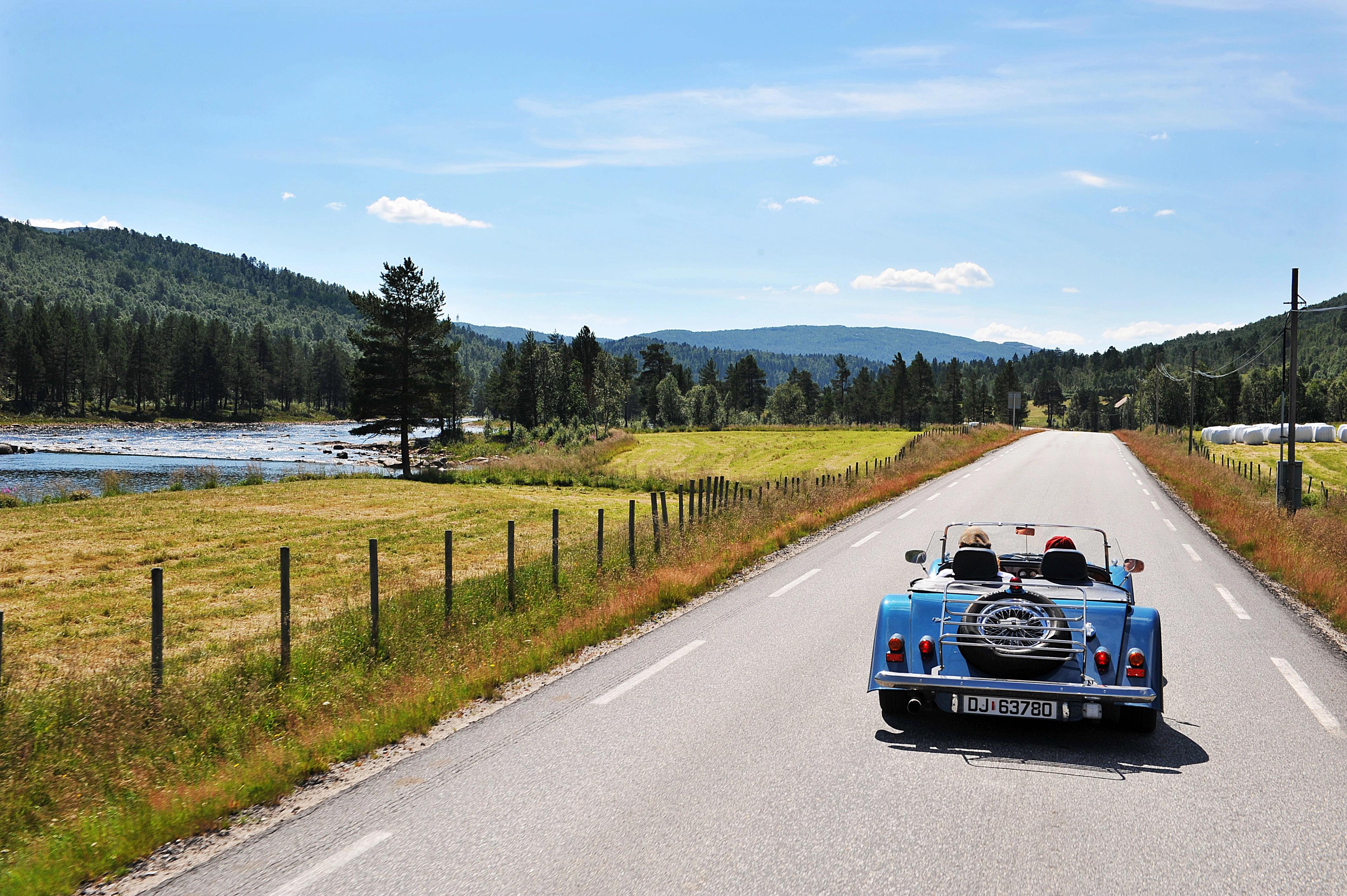 A blue cabriolet car on a road in Setesdal, Southern Norway