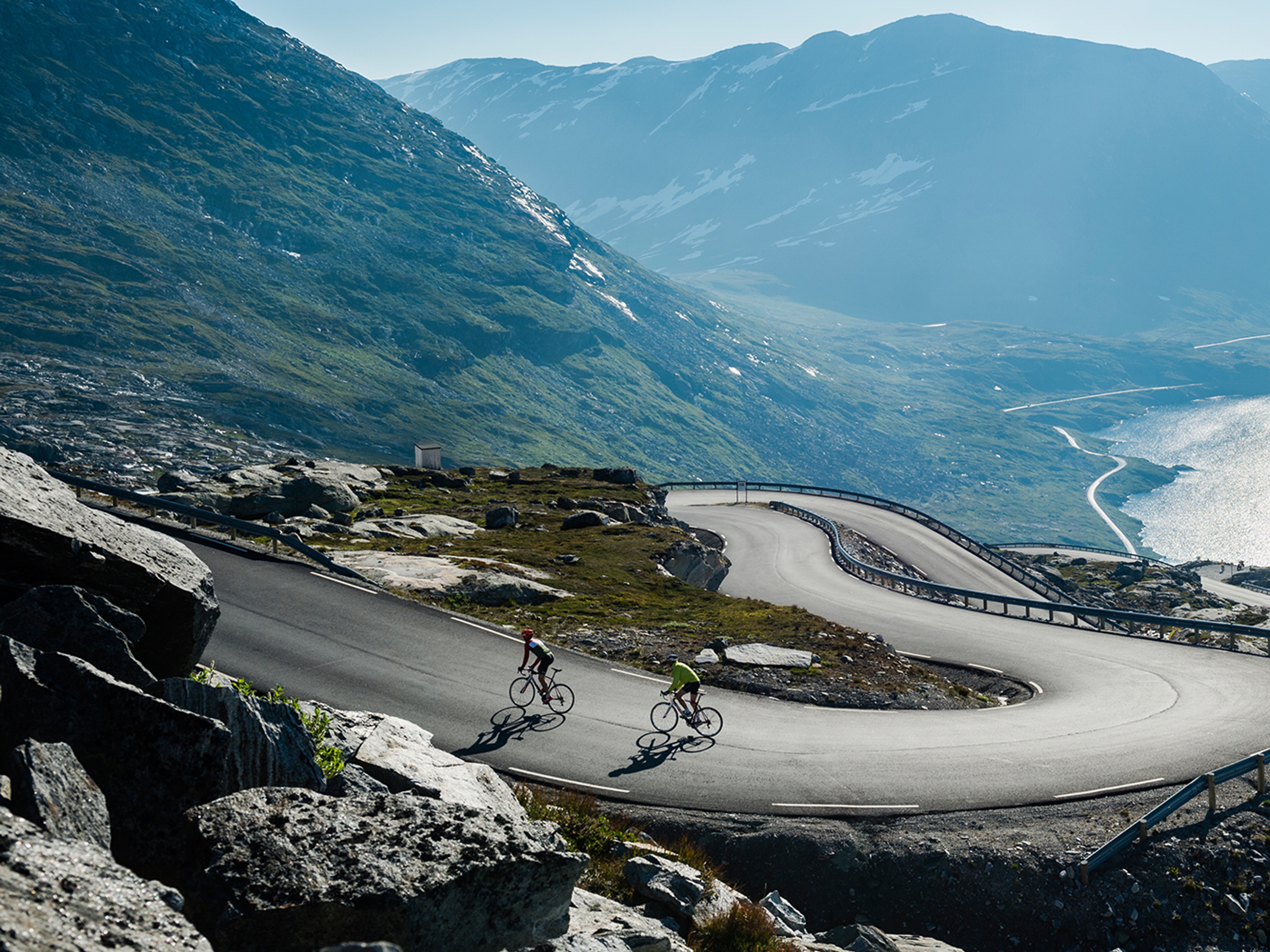 Zwei Radfahrer auf einer kurvenreiche Straße über dem Geirangerfjord in Fjord Norwegen