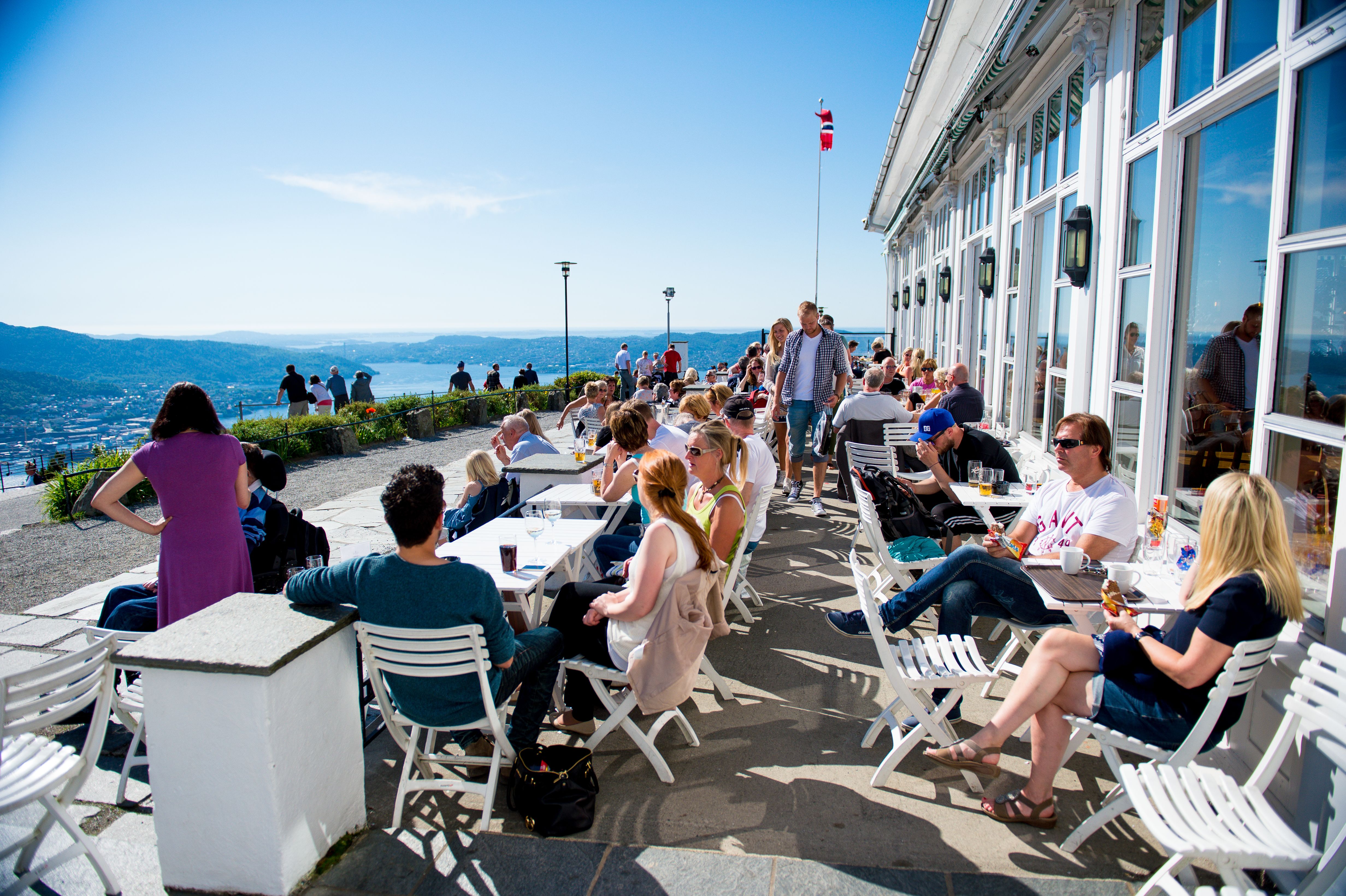 A group of people enjoying the view over Bergen from the restaurant at the Fløyen mountain in Norway