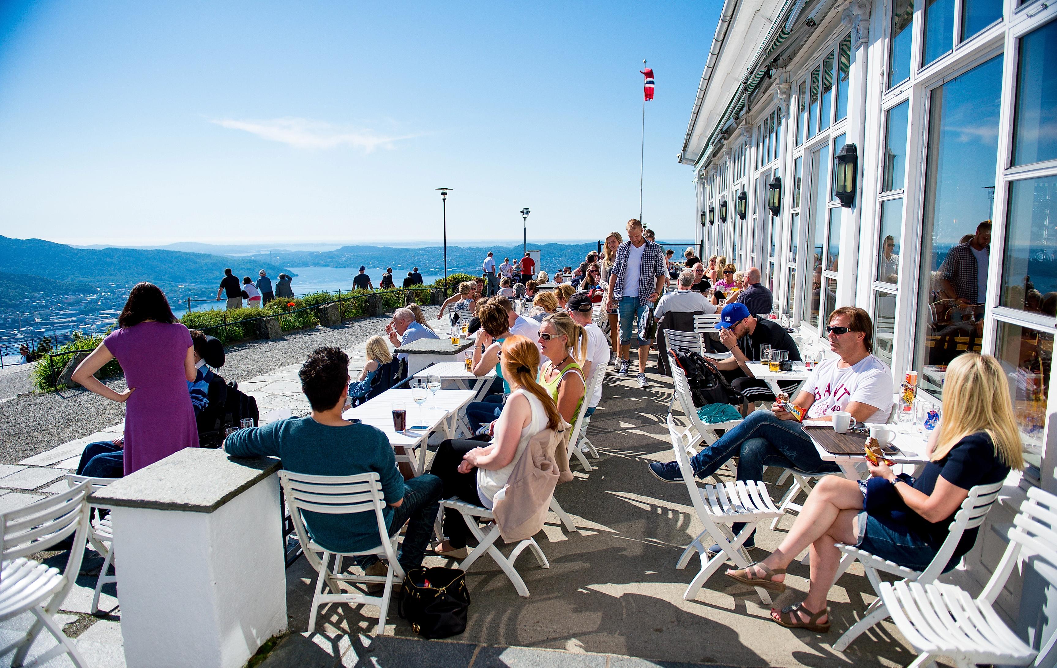 A group of people enjoying the view over Bergen from the restaurant at the Fløyen mountain in Norway