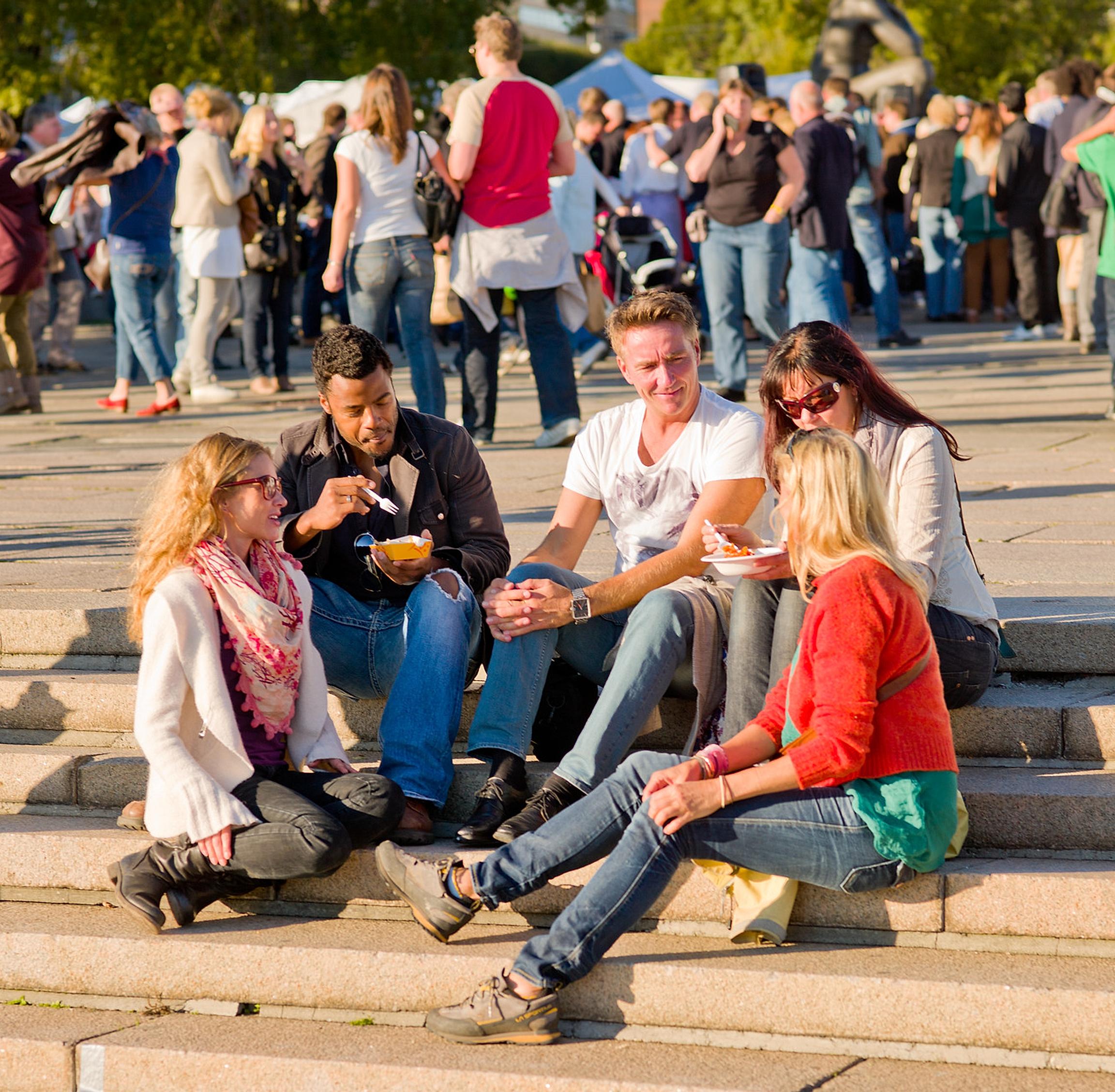 Folk som spiser mat i solen på matfestival